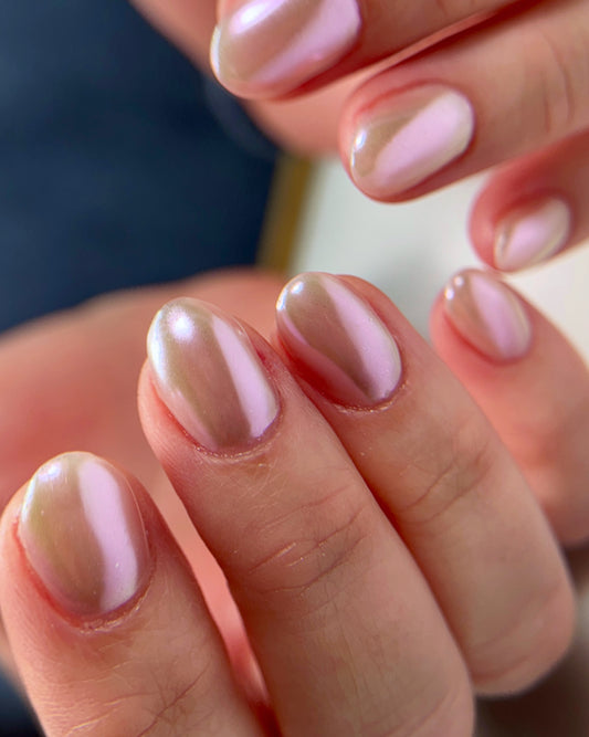 Close-up of a hand with chrome nail design on a blurred background