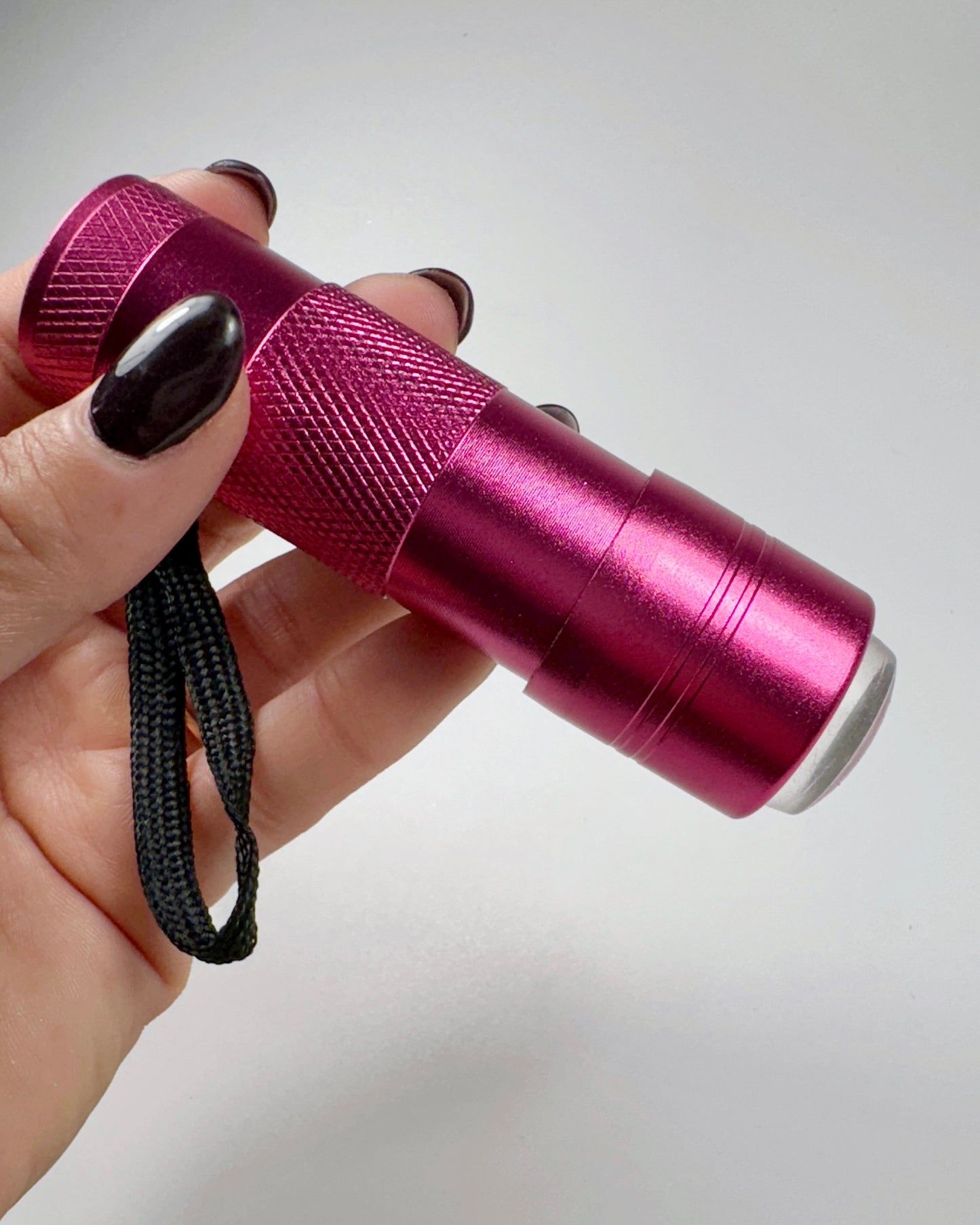 Hand holding small flashlight against white background 
