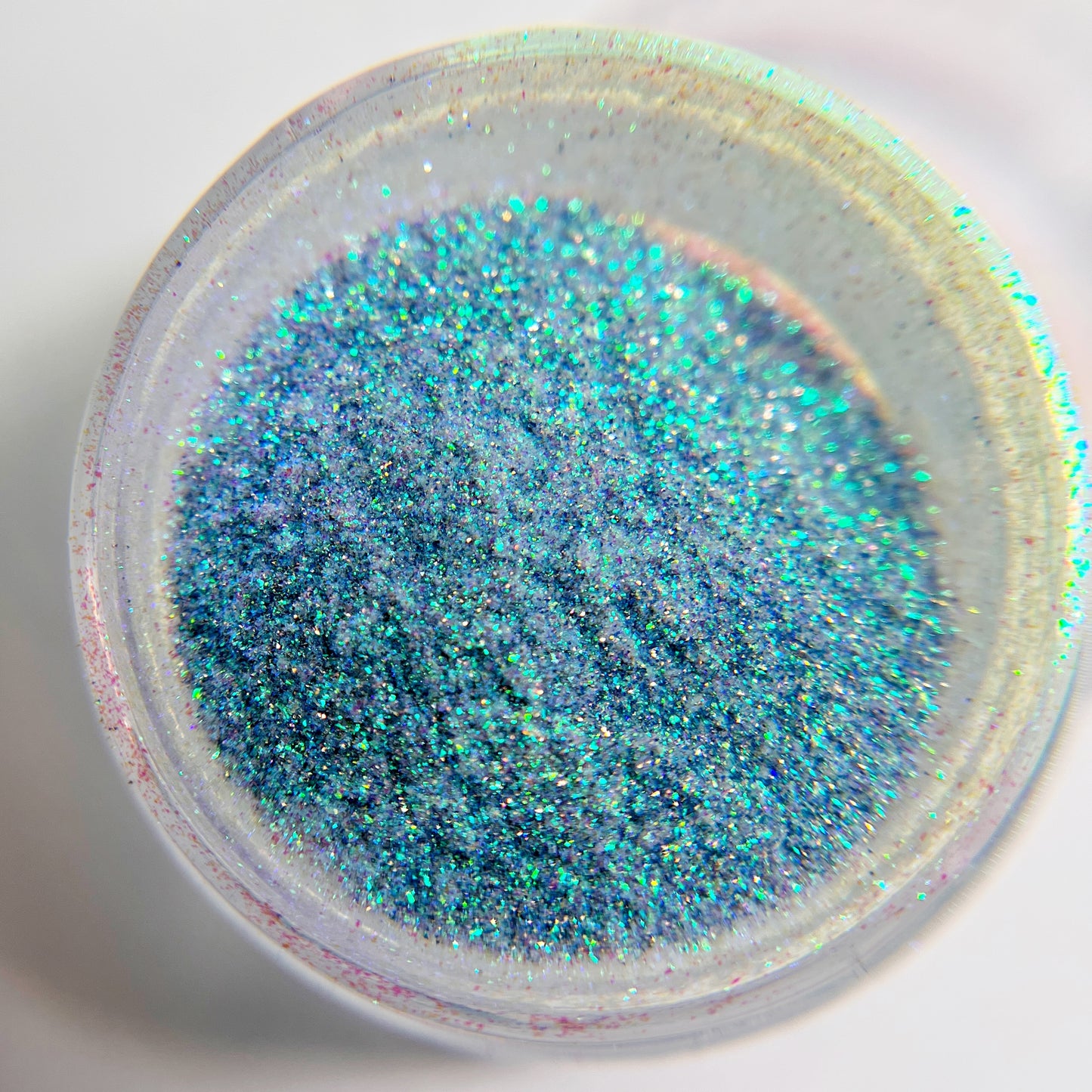 Close up of fine glitter in transparent jar against white background 