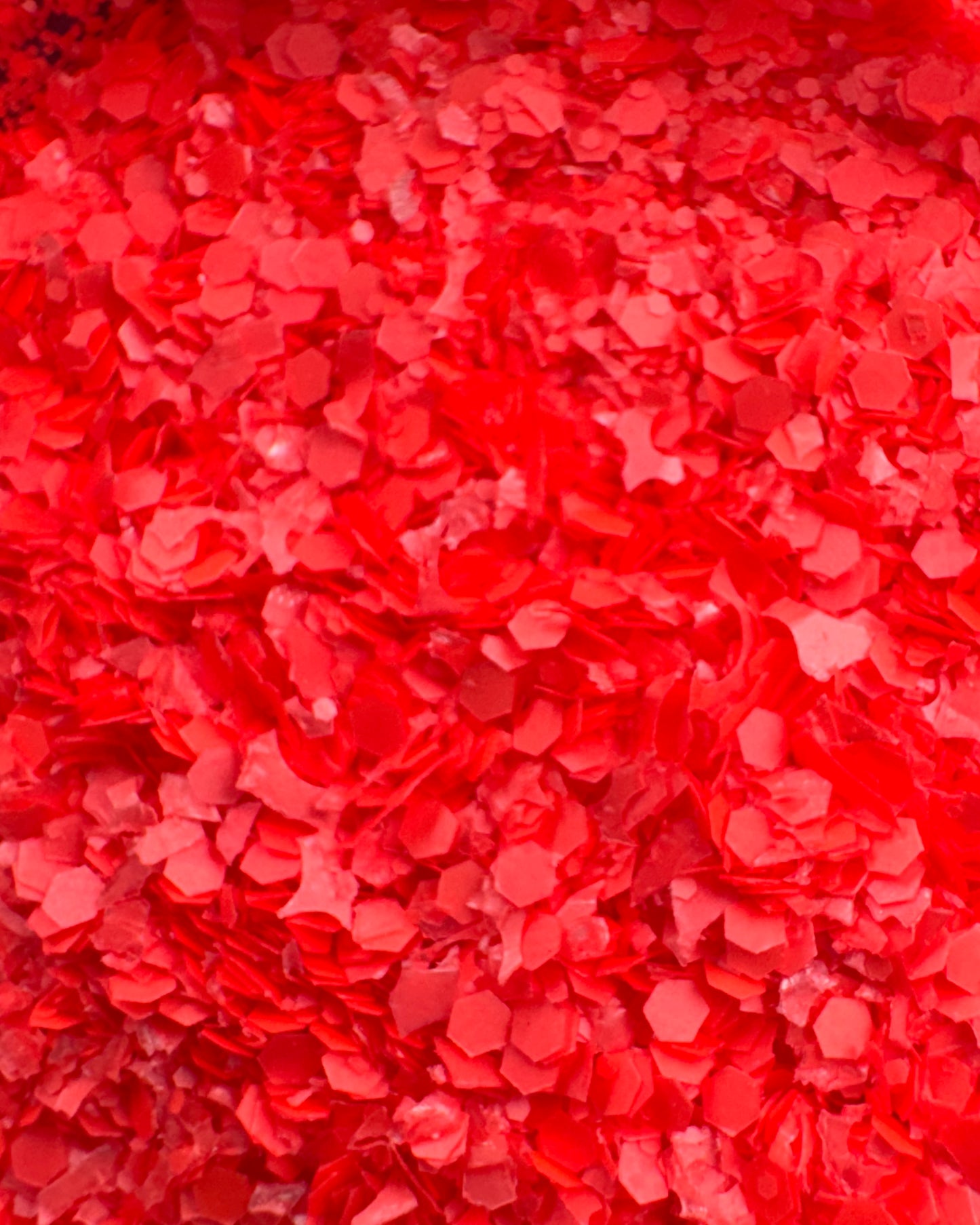 Detail view of textured glitter in neon red-orange color.