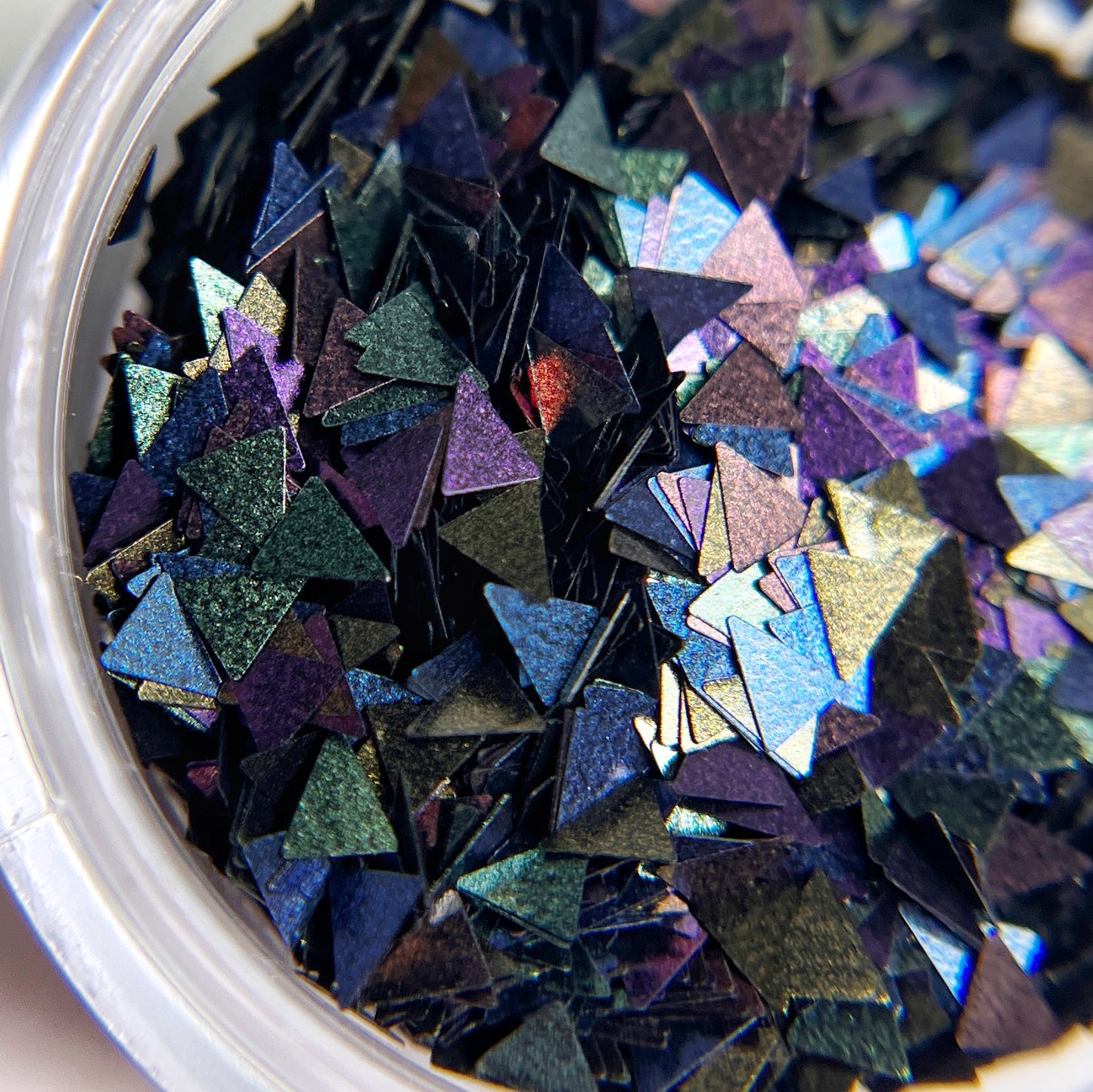 Close up of triangle shaped glitter in clear jar. 