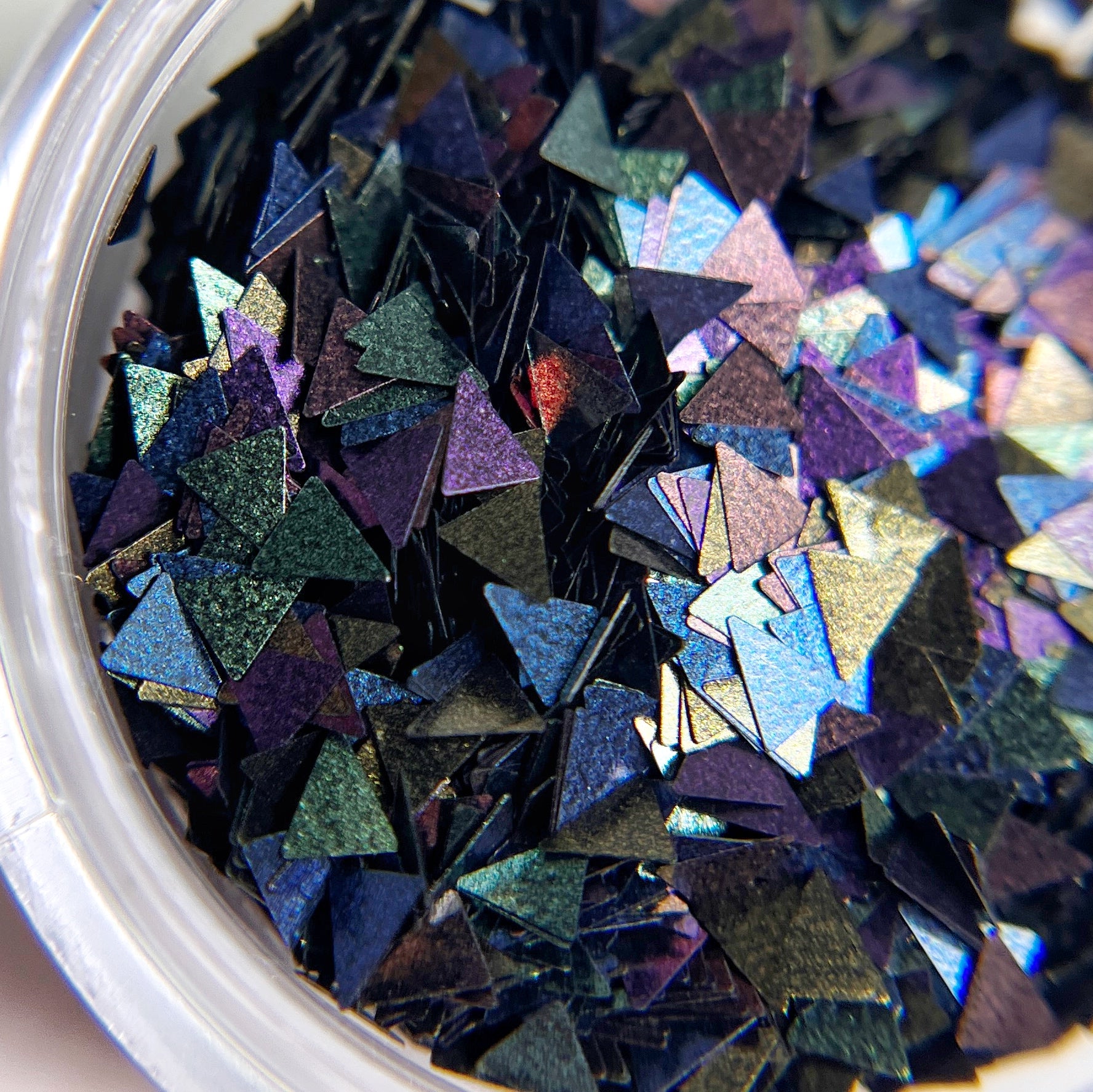 Close up of triangle shaped glitter in clear jar. 