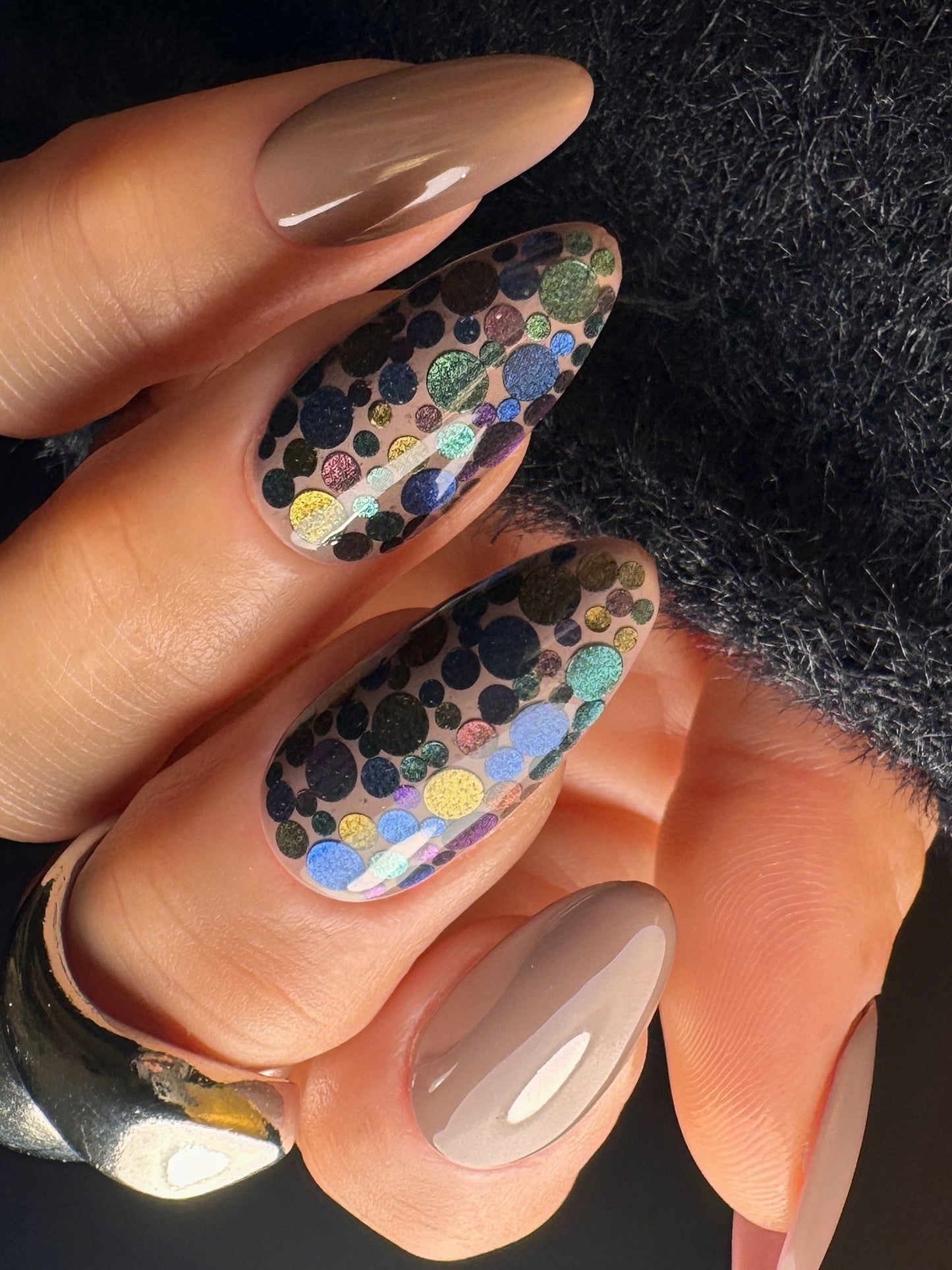 Nail art with multicolored dots on a textured background