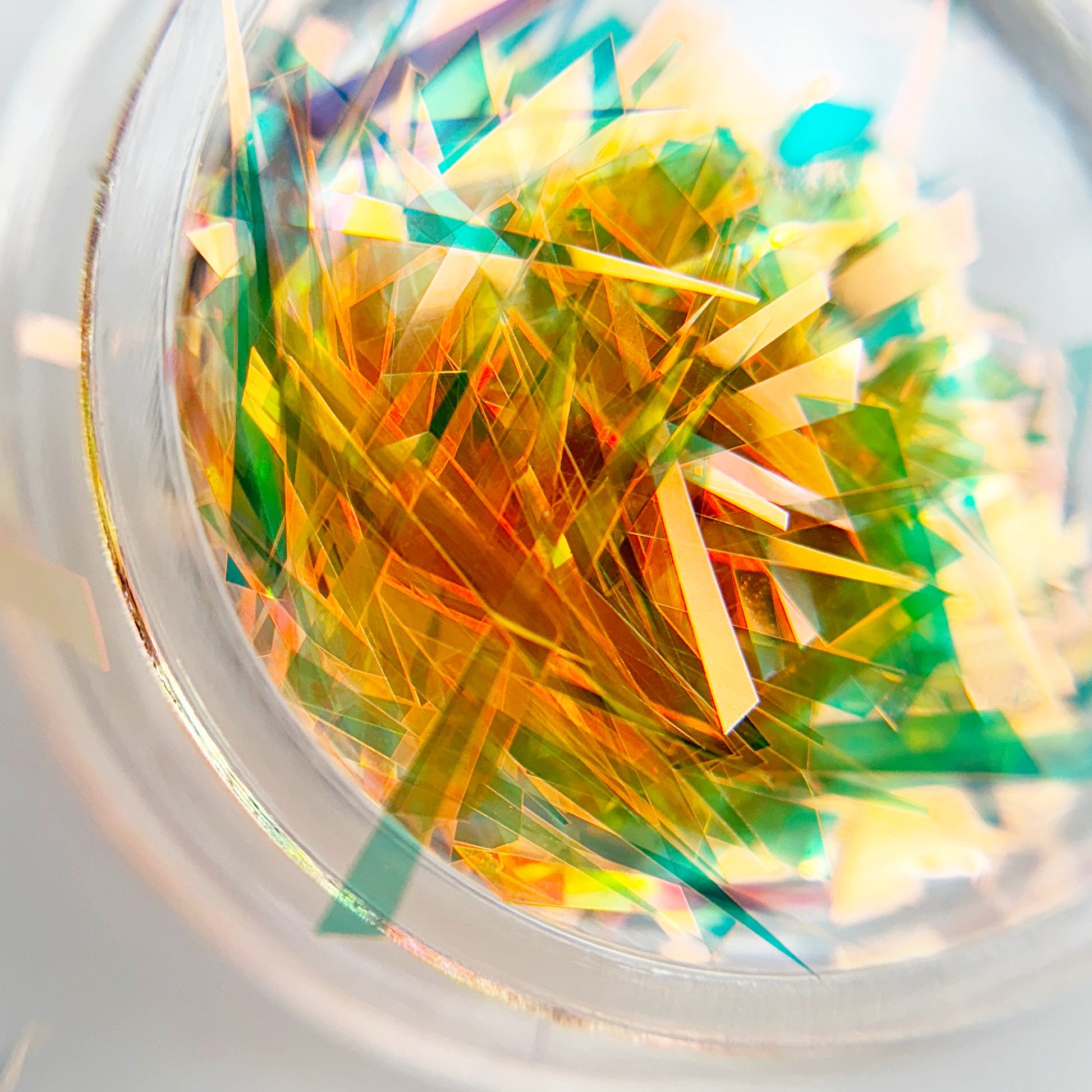A close-up view of multicolored shattered foil pieces inside a container, intended for nail art.