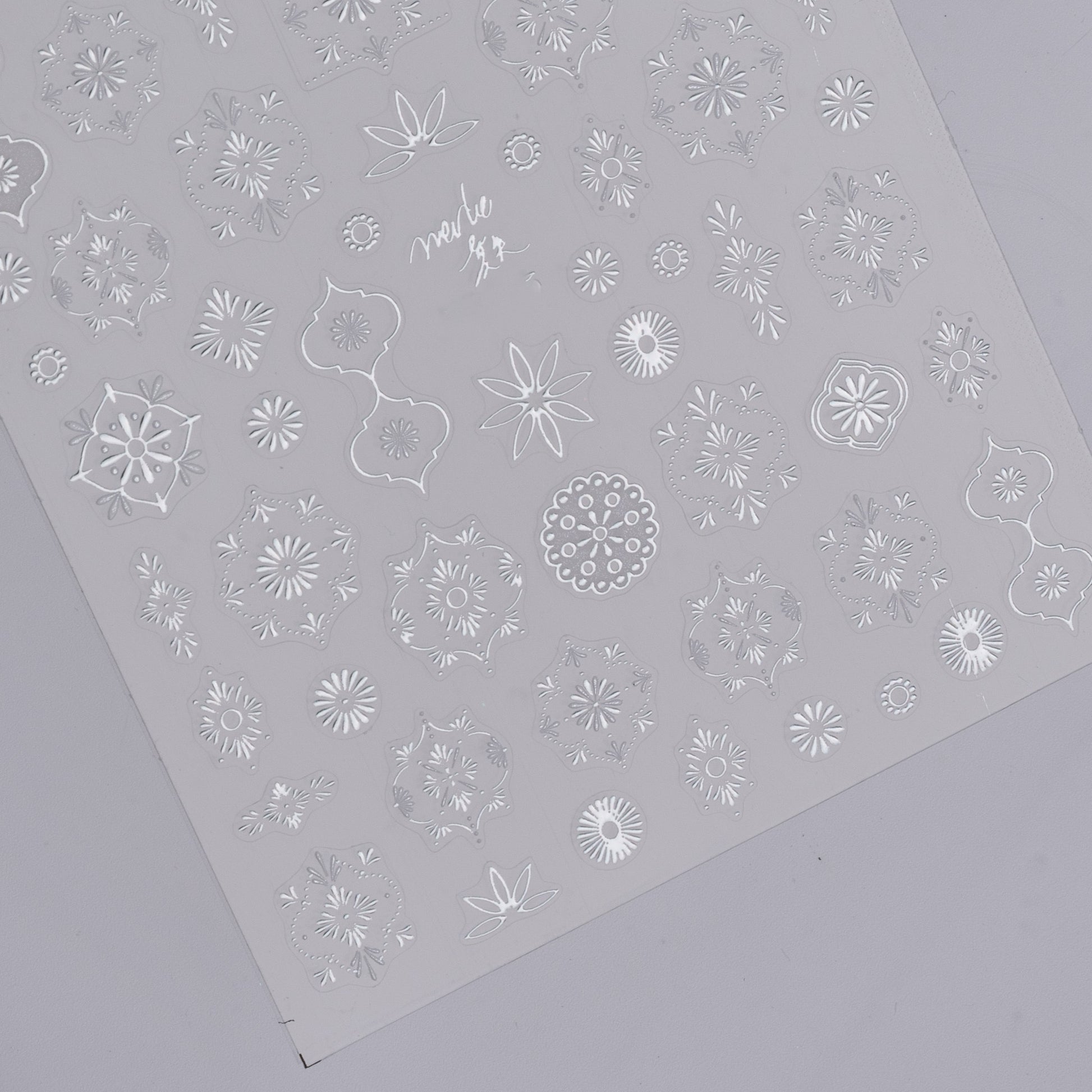 Detail view of silver nail decal sheet on light background.