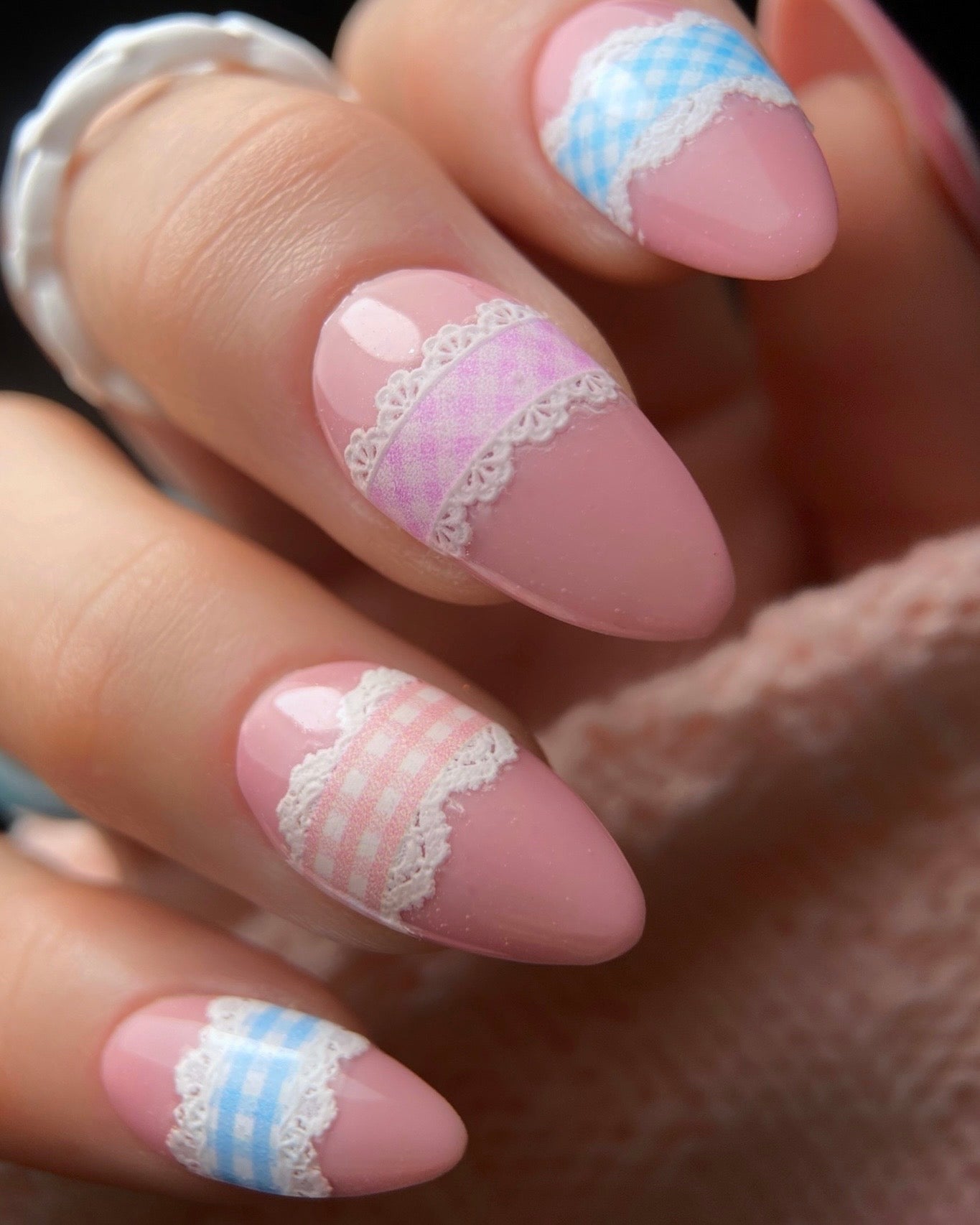Nails with pink and white lace design on a blurred background