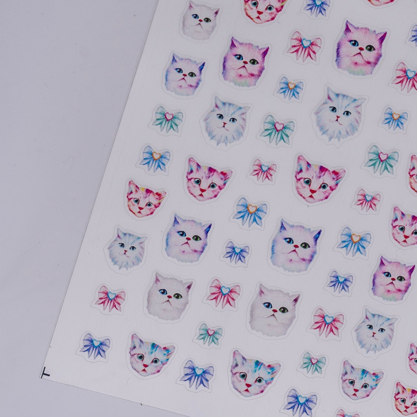 Sheet of stickers with cat faces and bows on a white background