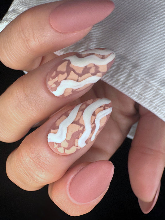 Nail art with wavy patterns and mosaic design on a neutral background