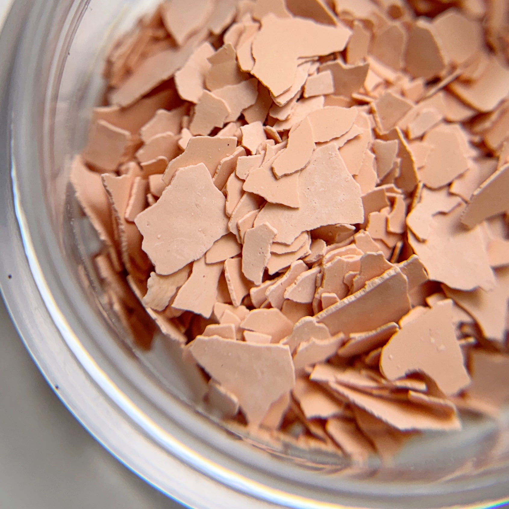 Close up of matte peach flakes intended for nail art.