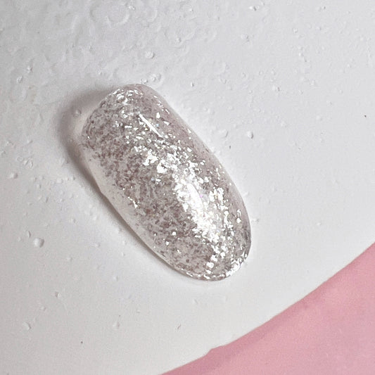Decorated nail tip on textured white surface and pink background.