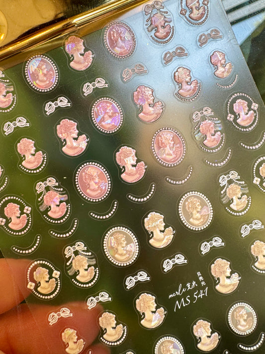 Sheet of decorative stickers with vintage-style illustrations on a reflective surface.