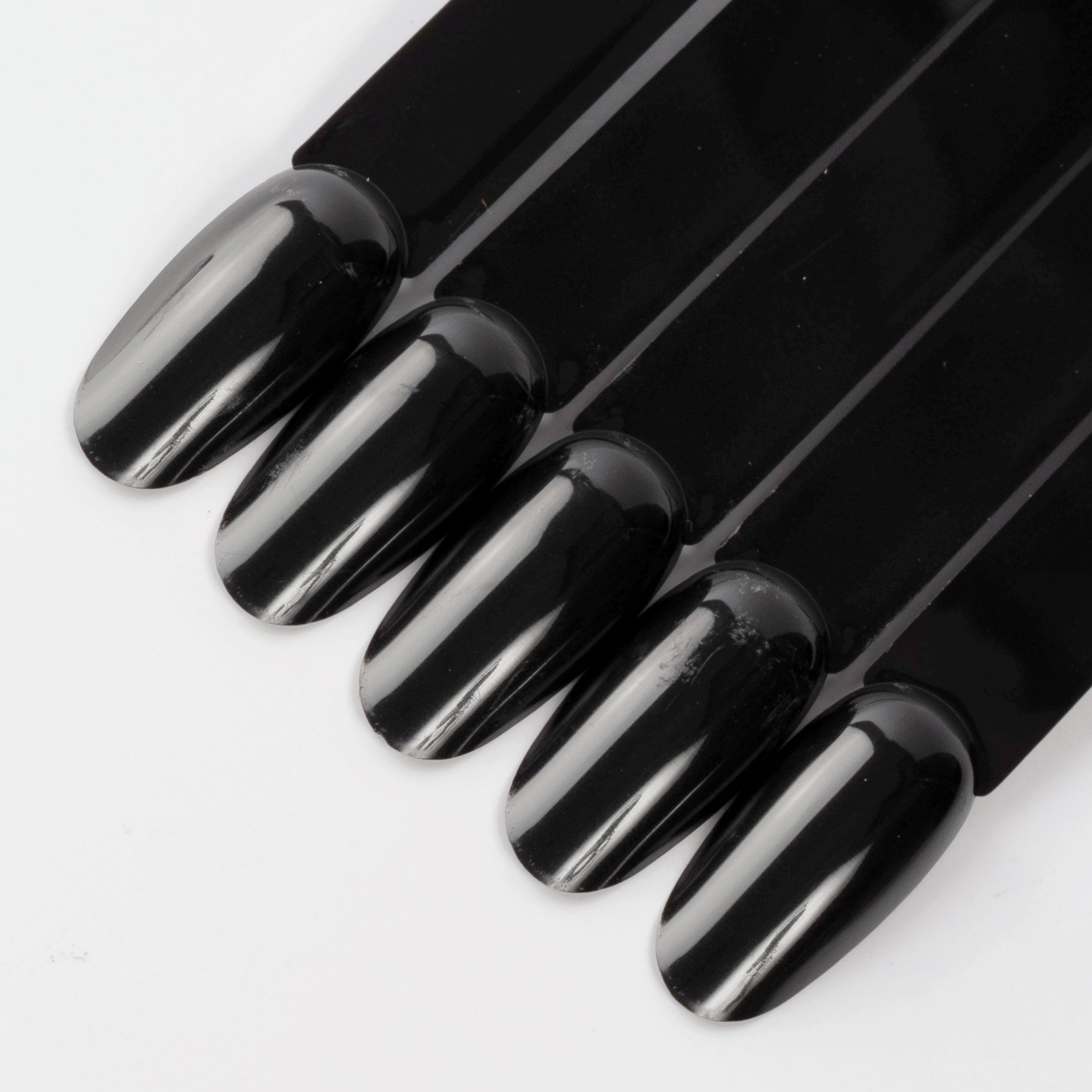 Black oval nail swatch sticks on white background.