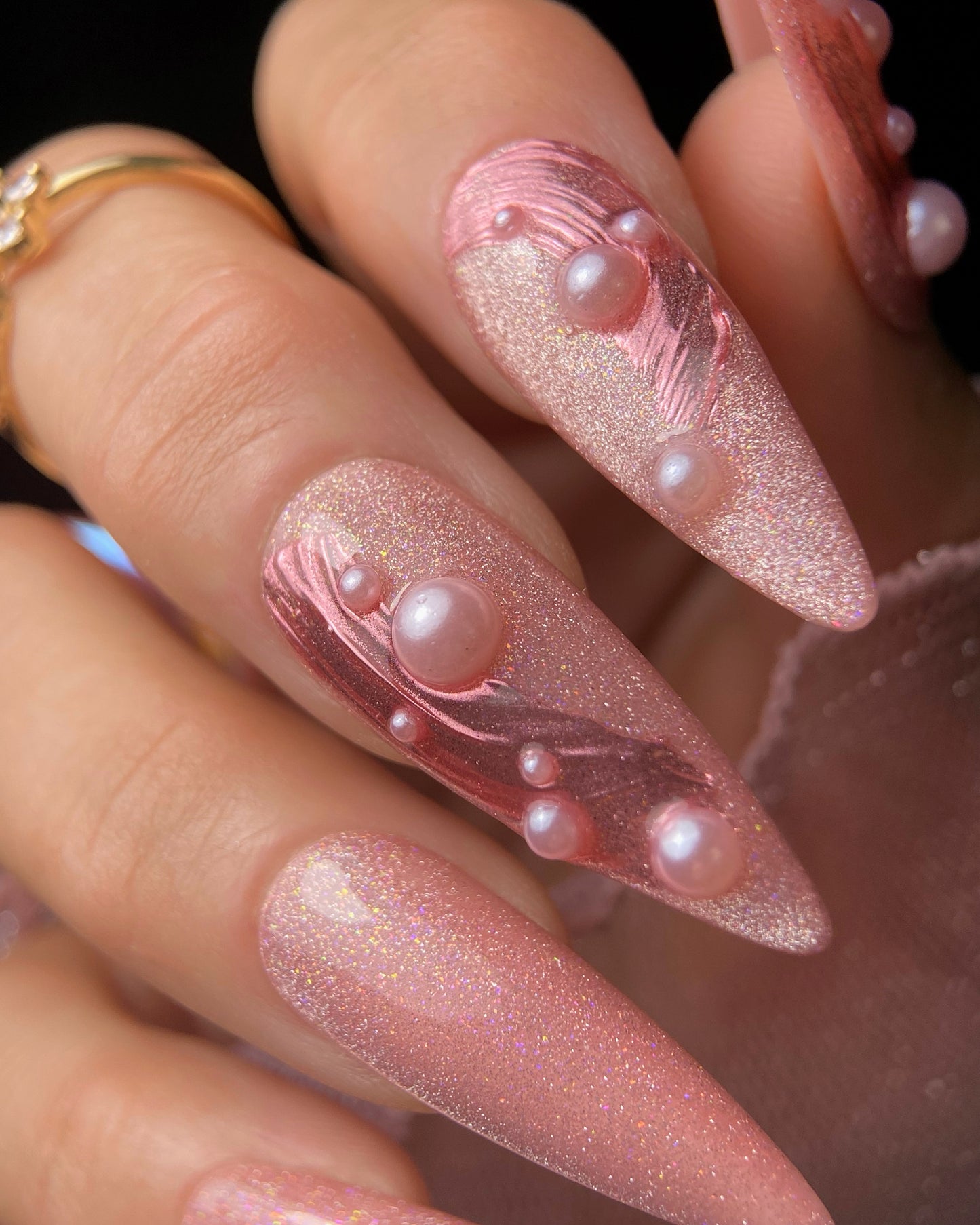 Pink glittery nails with pearl accents on a hand
