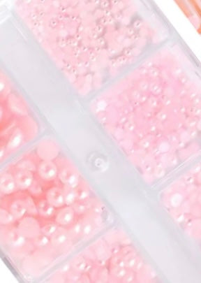 Small pink beads in a clear container with compartments.