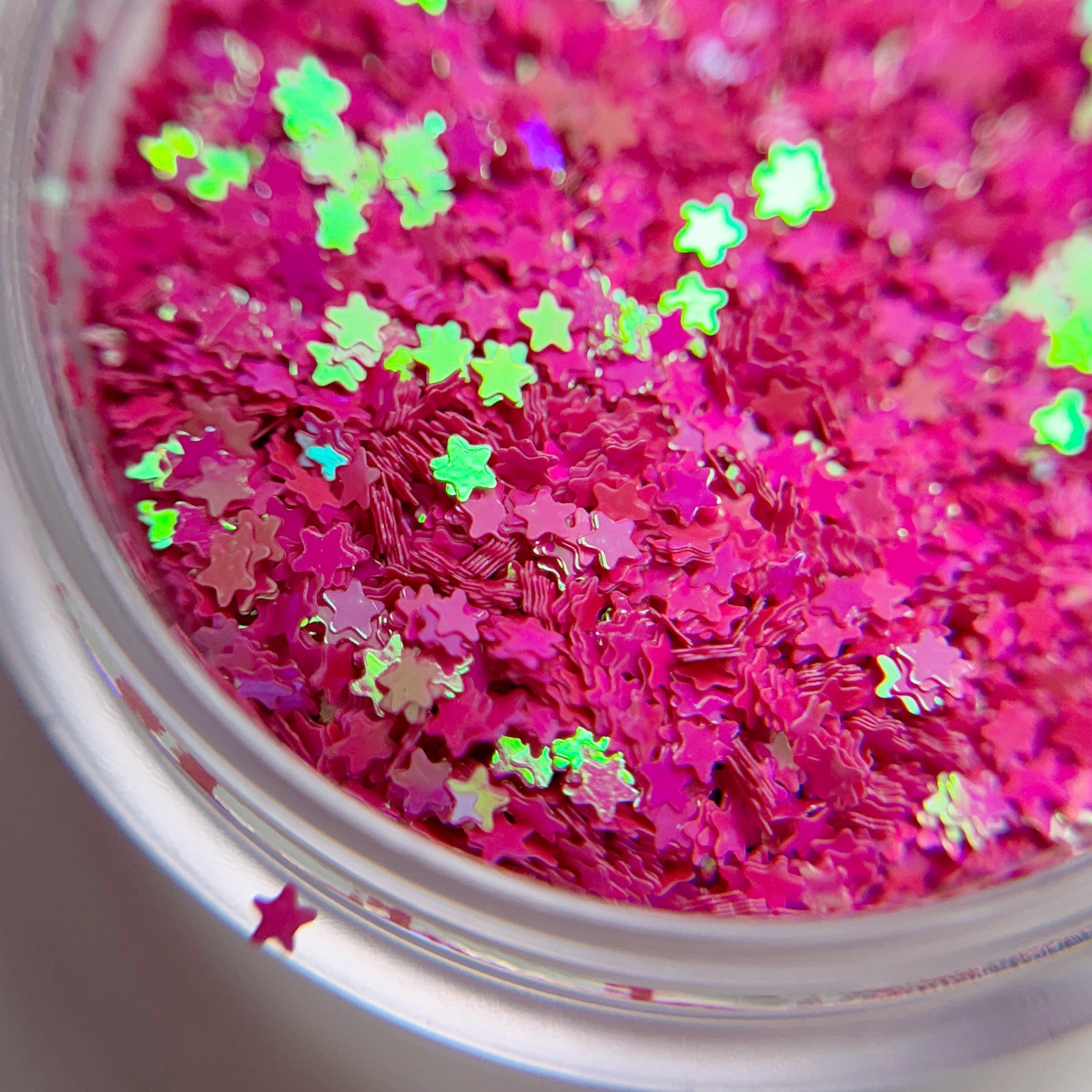A close-up view of pink star-shaped glitter in a container.
