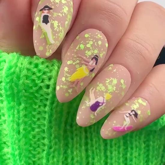 Video of nails with cartoon design and green glitter on neutral background.