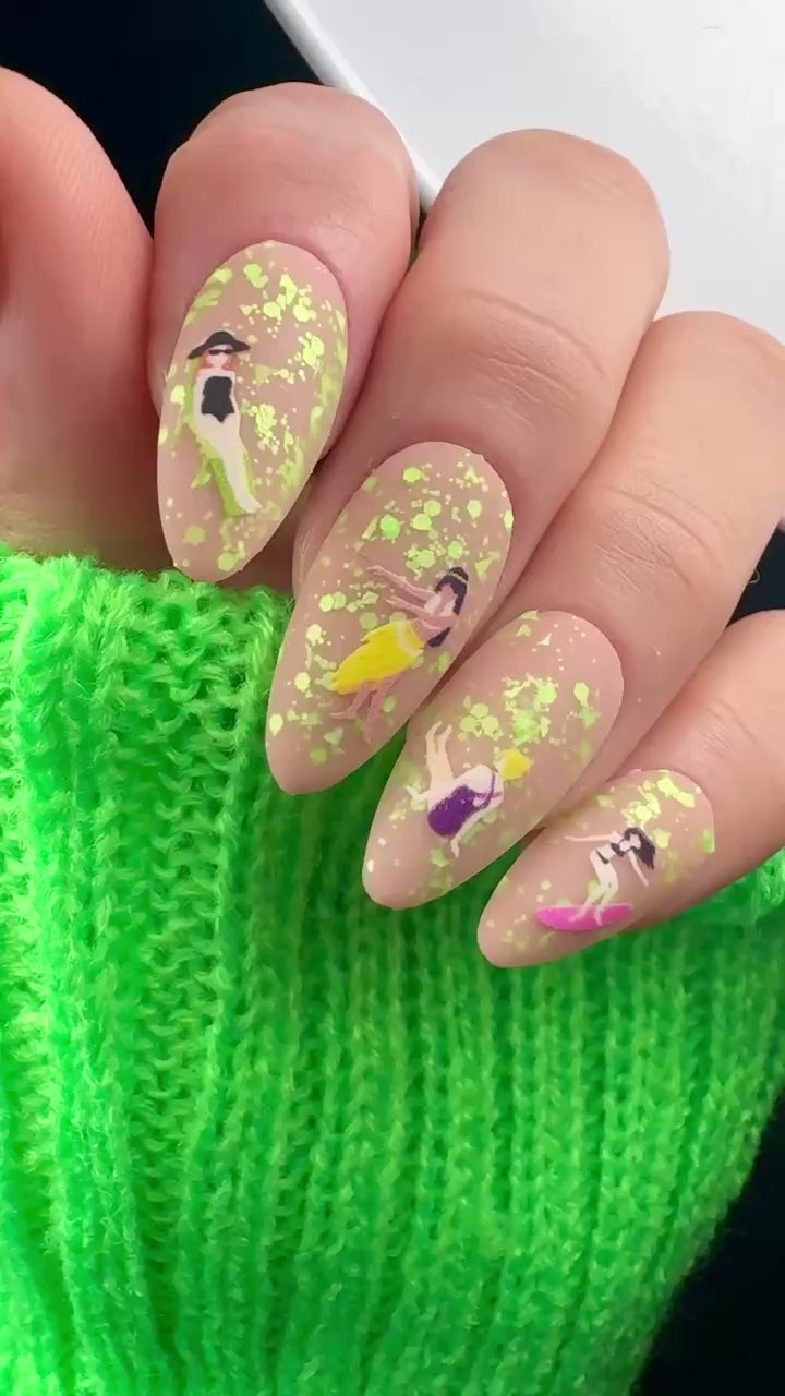 Video of nails with cartoon design and green glitter on neutral background.
