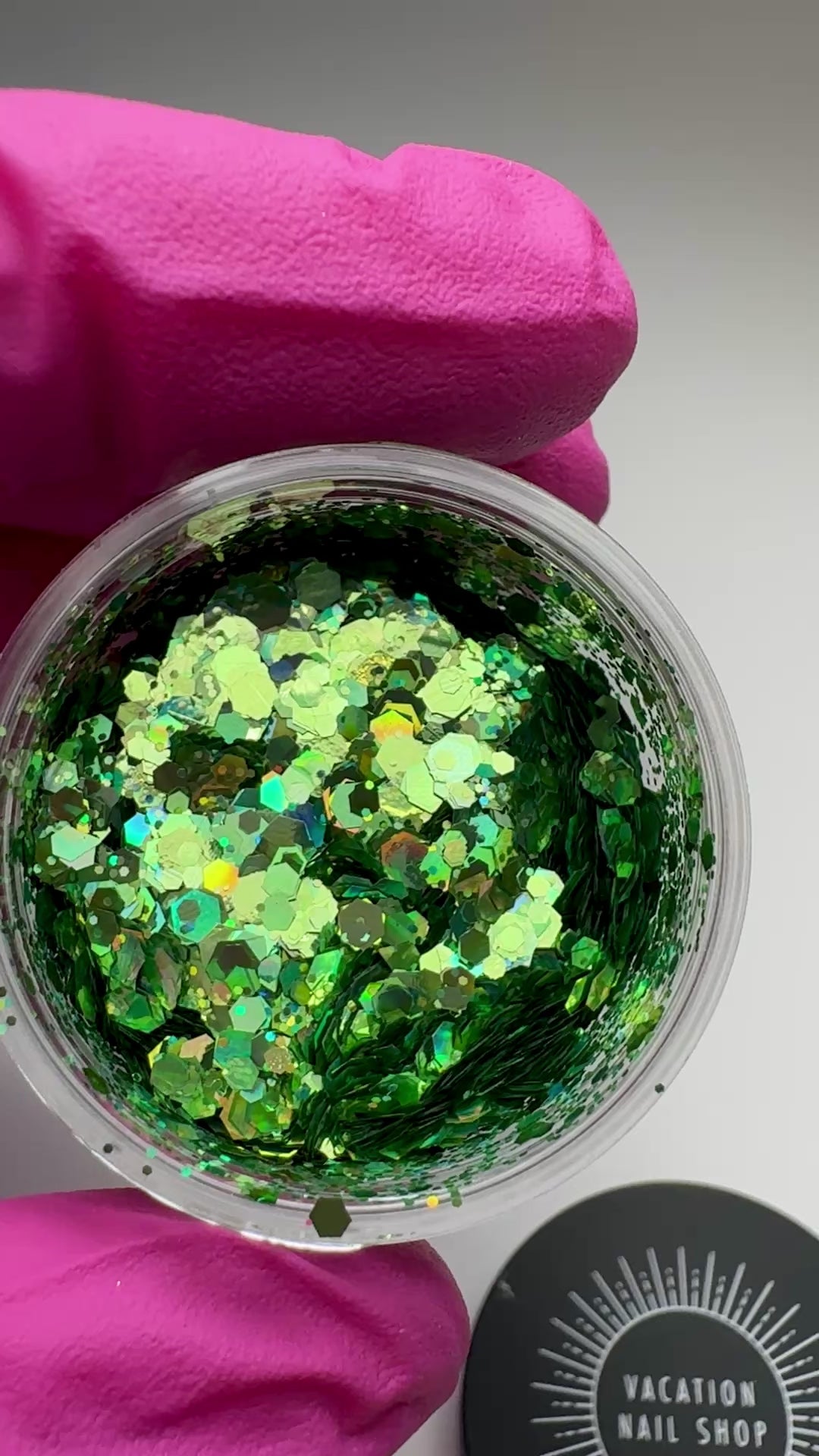 Video of hand in pink glove holding clear jar with textured glitter.