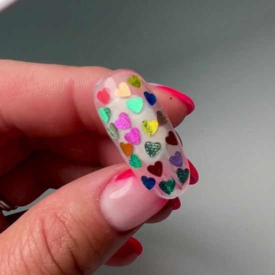 Video of Cloce up of multi-color heart glitter in clear jar on white background. 