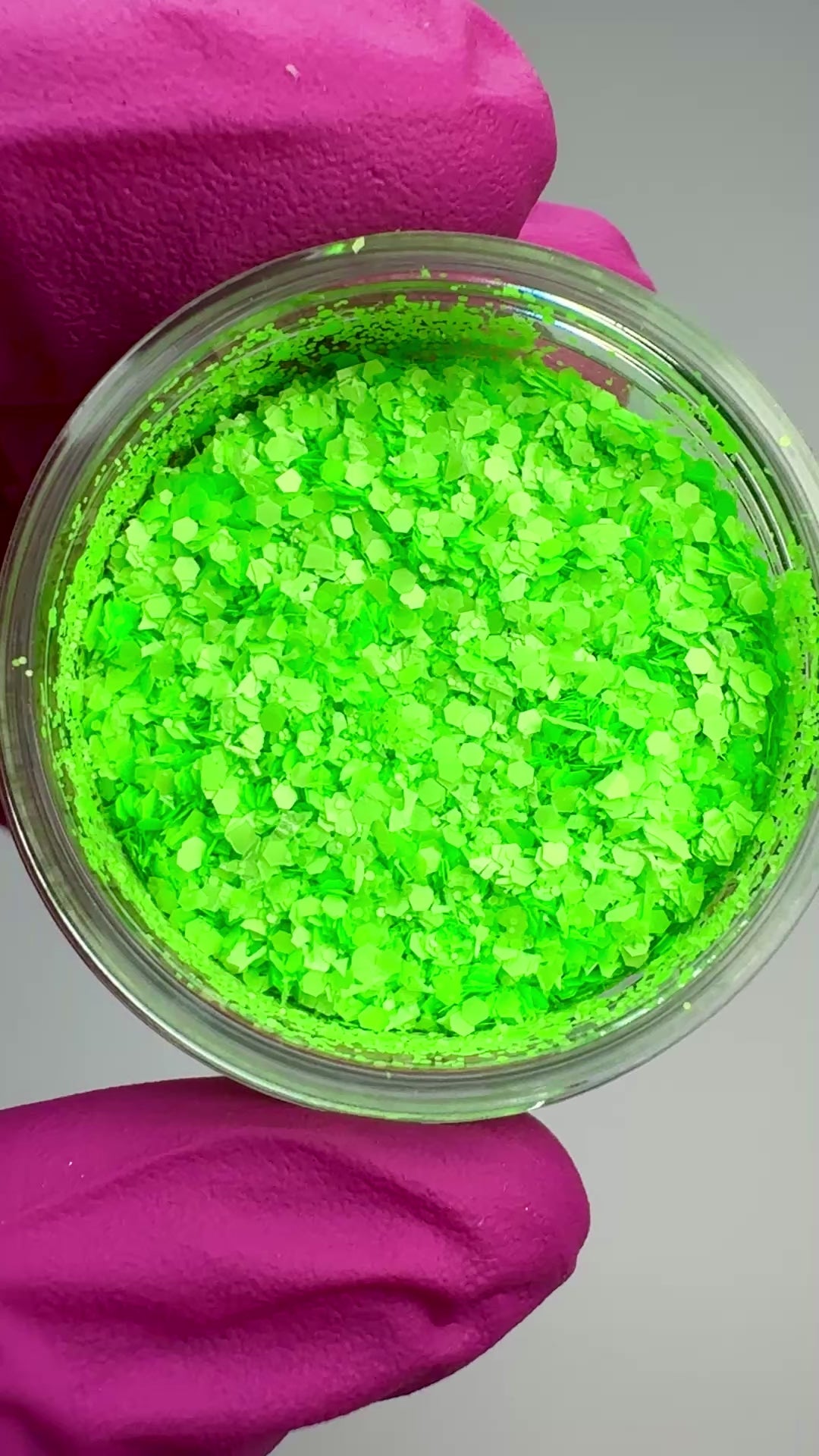 Video of hand in pink glove holding clear jar with textured glitter.