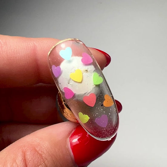 Video of hand holding decorated nail tip on gray backgroud. 