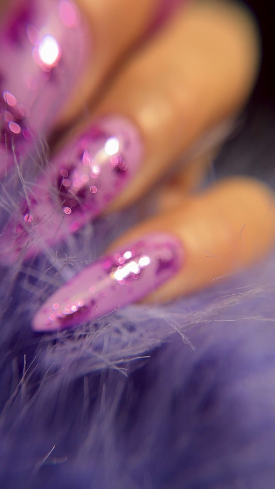 Close up of manicured hand with glittery nail art on blurred background