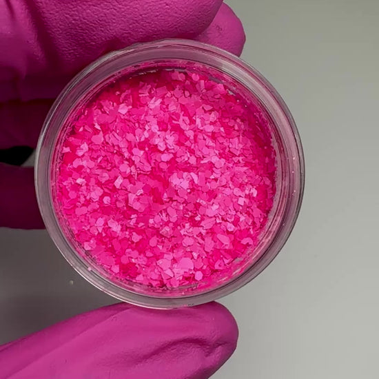 Video of hand in pink glove holding clear jar with textured glitter.
