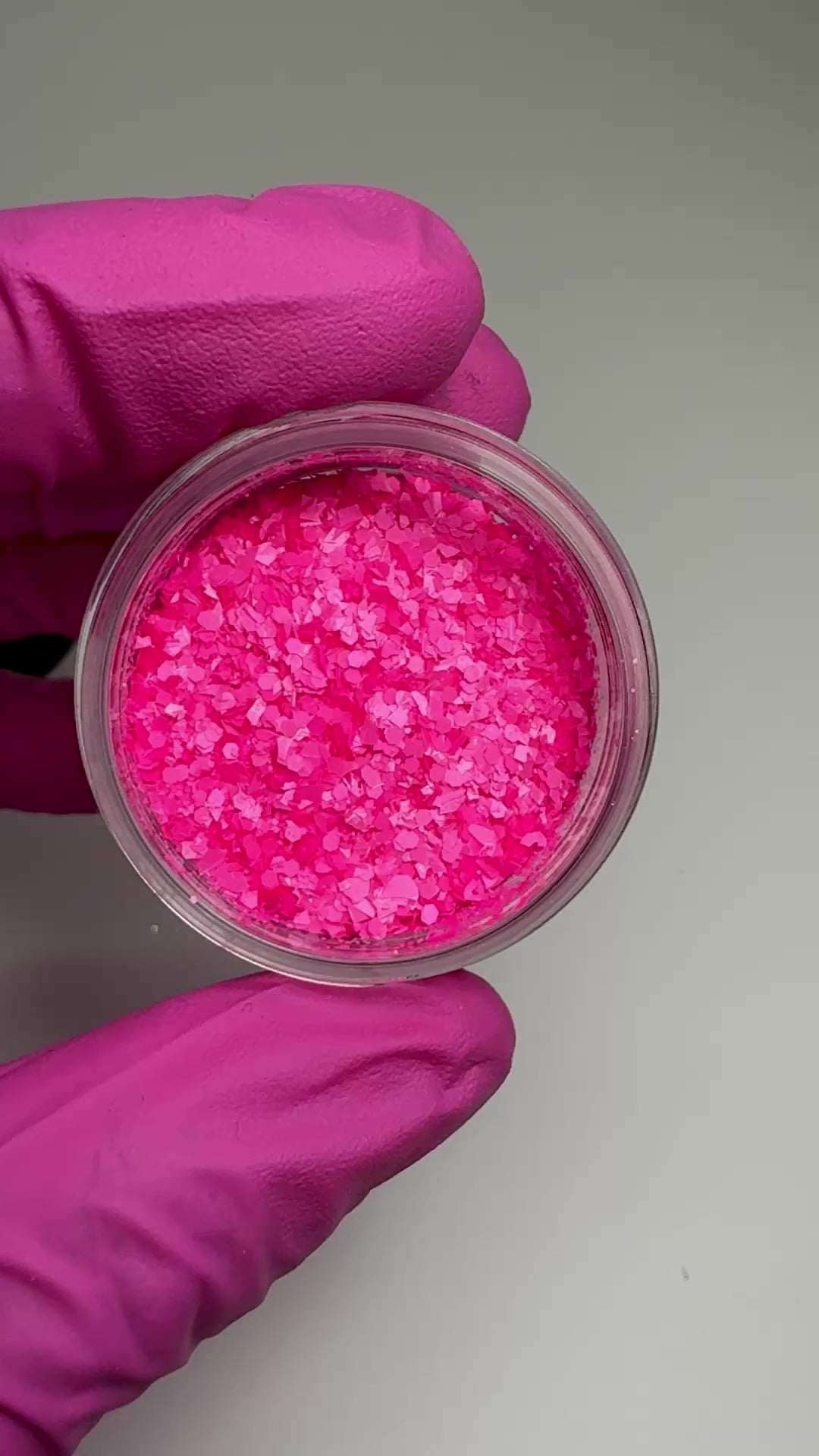 Video of hand in pink glove holding clear jar with textured glitter.
