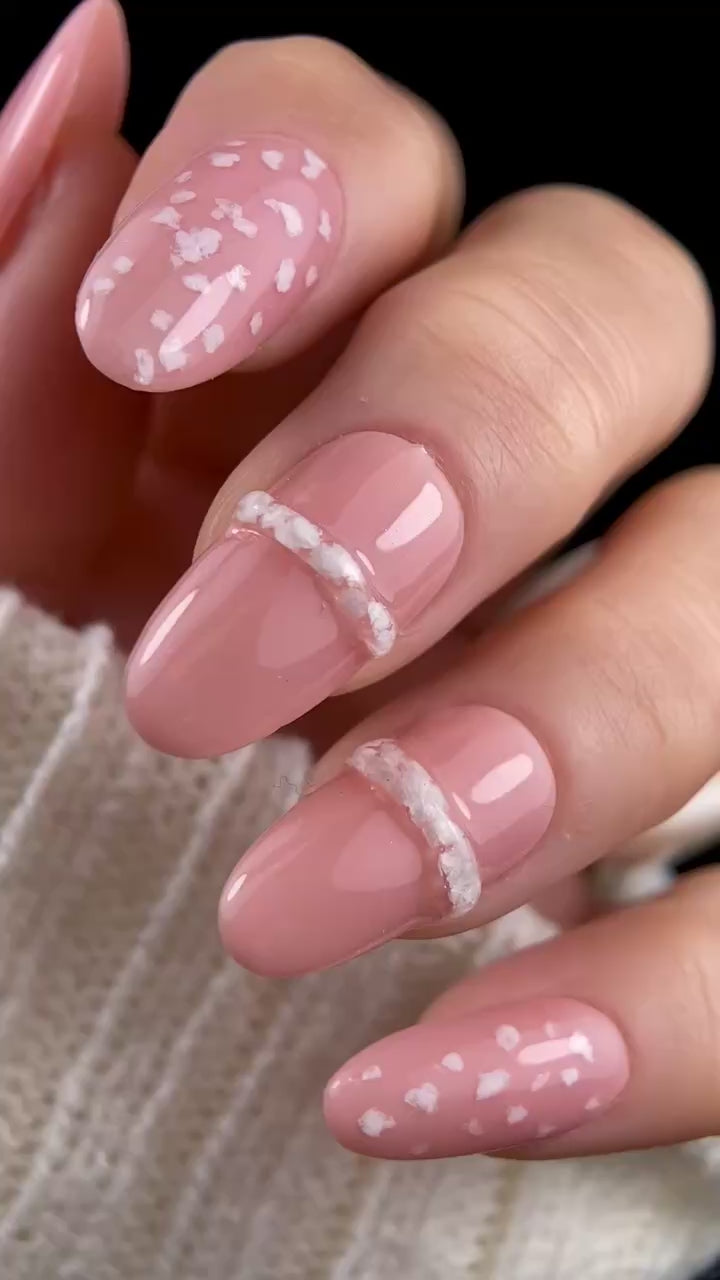 Video of manicured hand with pink nails and white nail art.