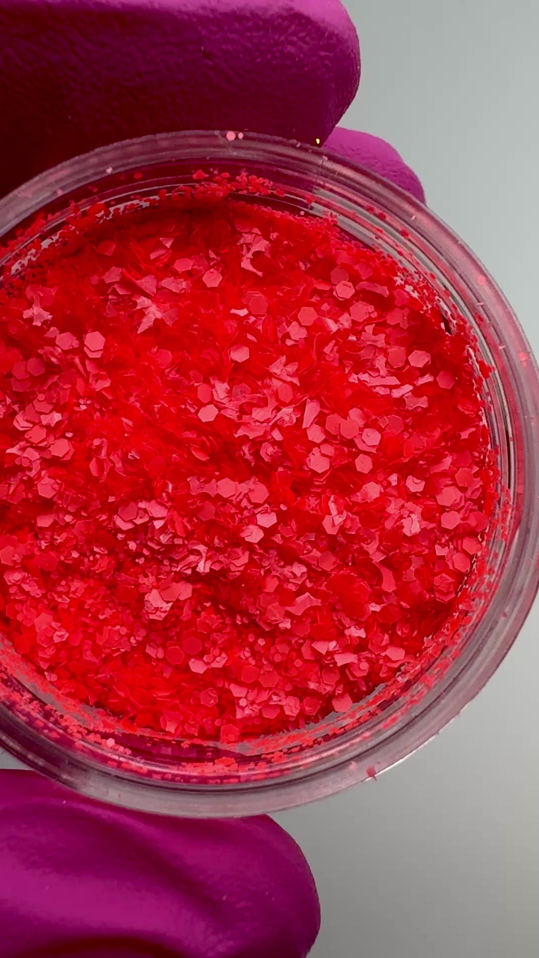 Video of hand in pink glove holding clear jar with textured glitter.