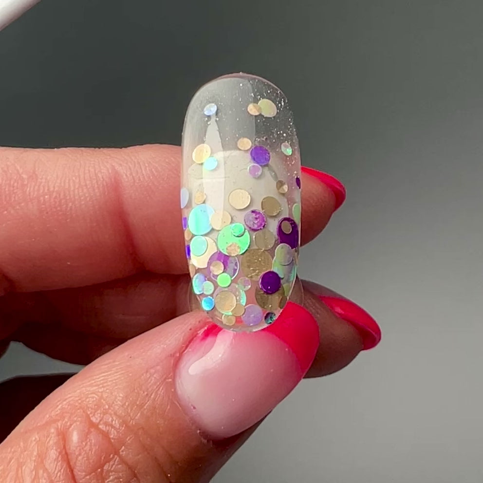 Video of a hand holding and showcasing a nail tip on gray backrgound. 