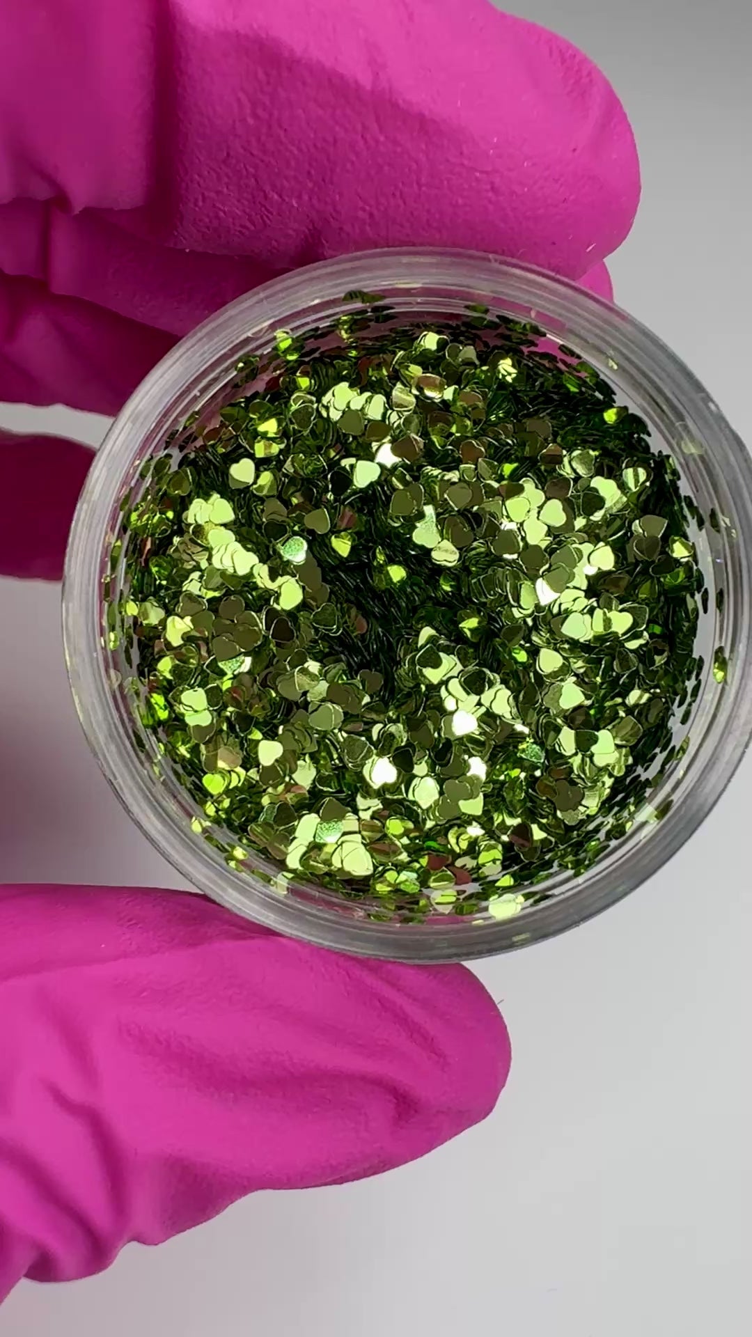 Video of gloved hand holding clear jar with textured glitter. 