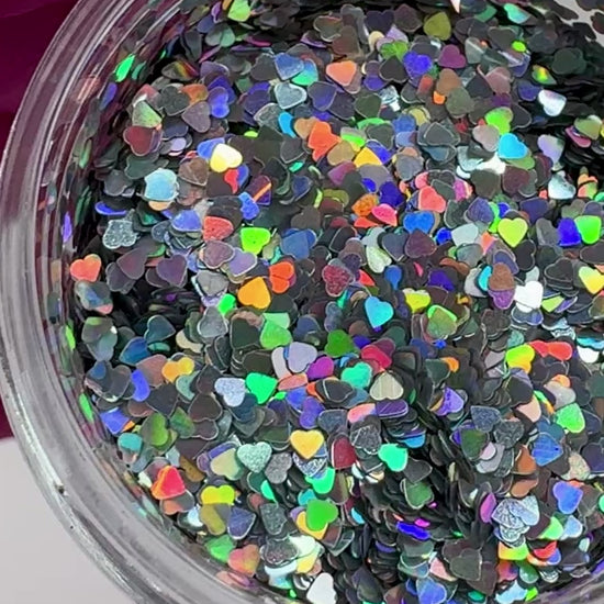 Video of gloved hand holding clear jar with textured glitter. 
