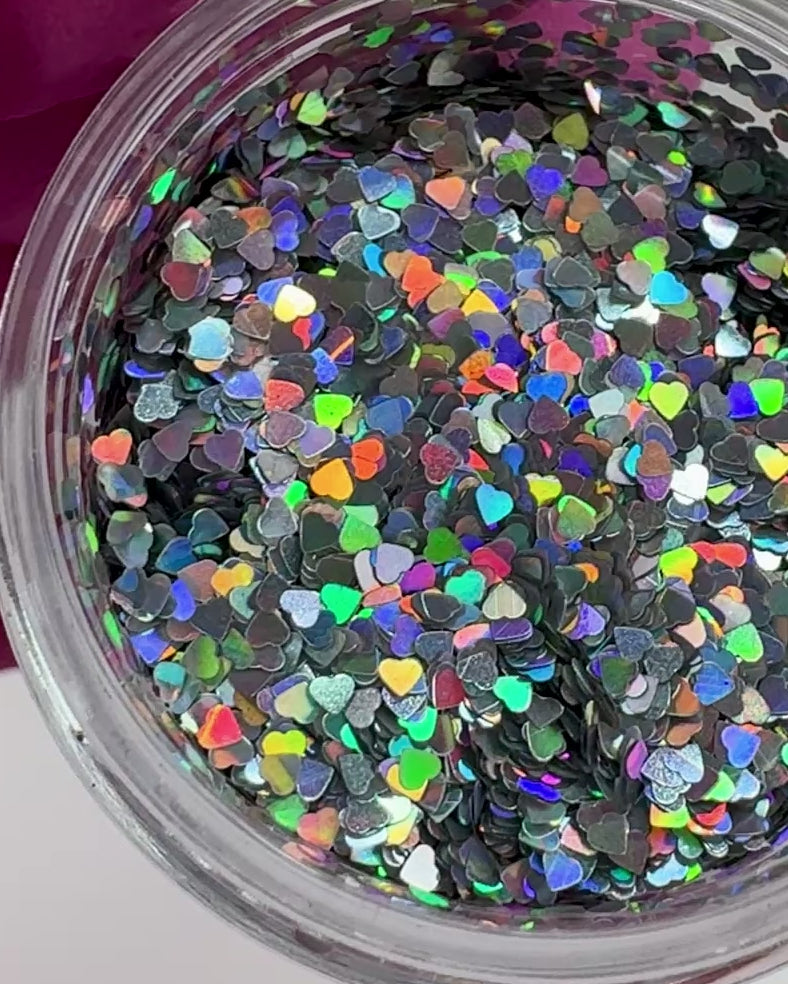 Video of gloved hand holding clear jar with textured glitter. 