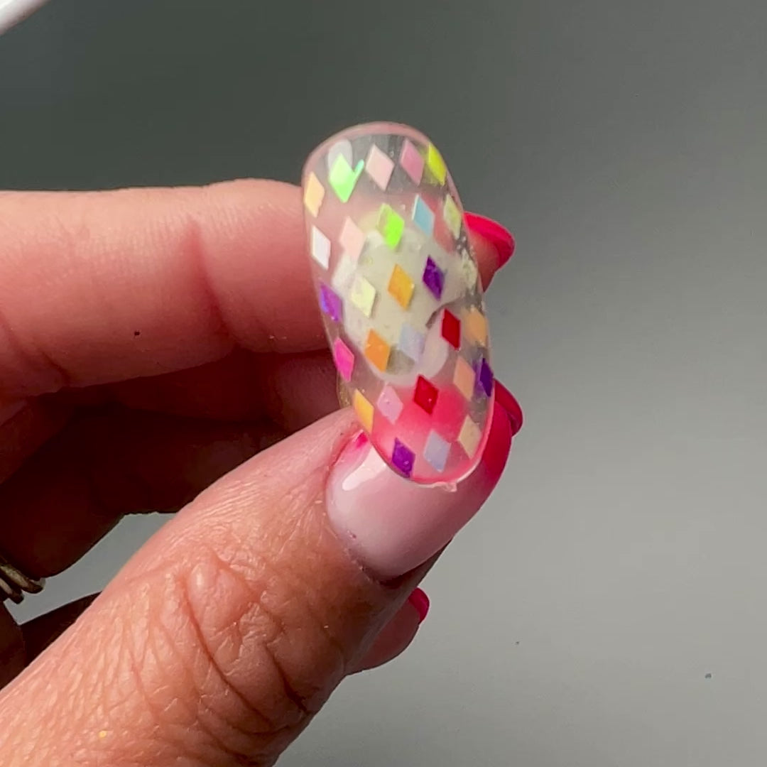 Video of hand holding decorated nail tip. 