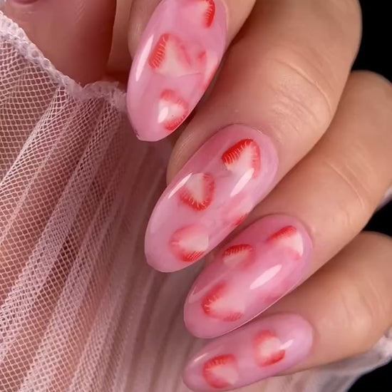 Video of pink nails with strawberry design with against black background. 