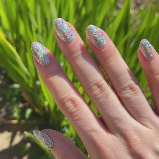 Video of a manicure by nail artist Katie Dutra using Vacation Nail Shop Mega Holo Chrome, with sparkling silver holographic nails flashing rainbow reflections as the hands move in natural light.