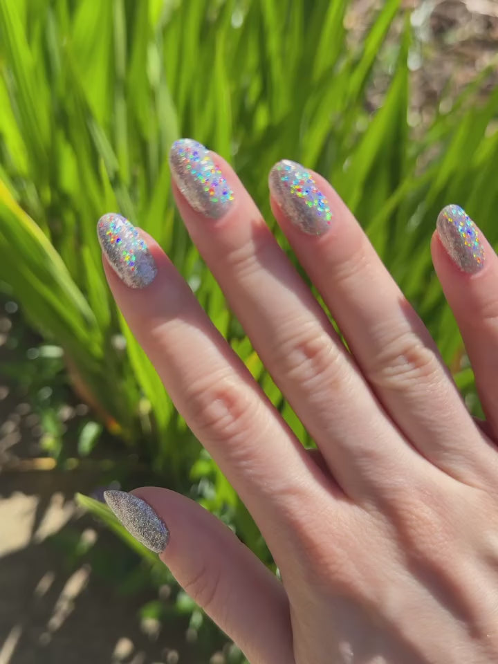 Video of a manicure by nail artist Katie Dutra using Vacation Nail Shop Mega Holo Chrome, with sparkling silver holographic nails flashing rainbow reflections as the hands move in natural light.