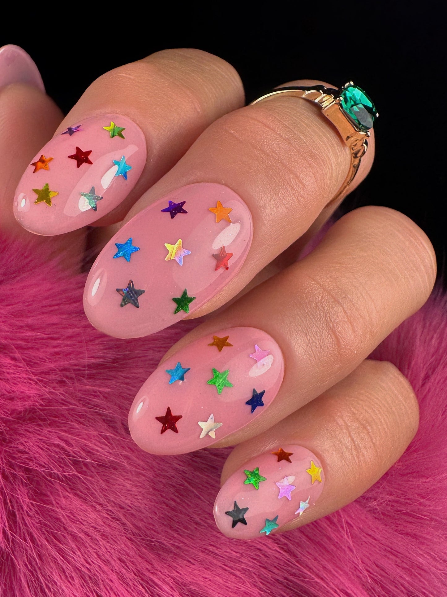 Pink nails with colorful star decorations on a pink fur background