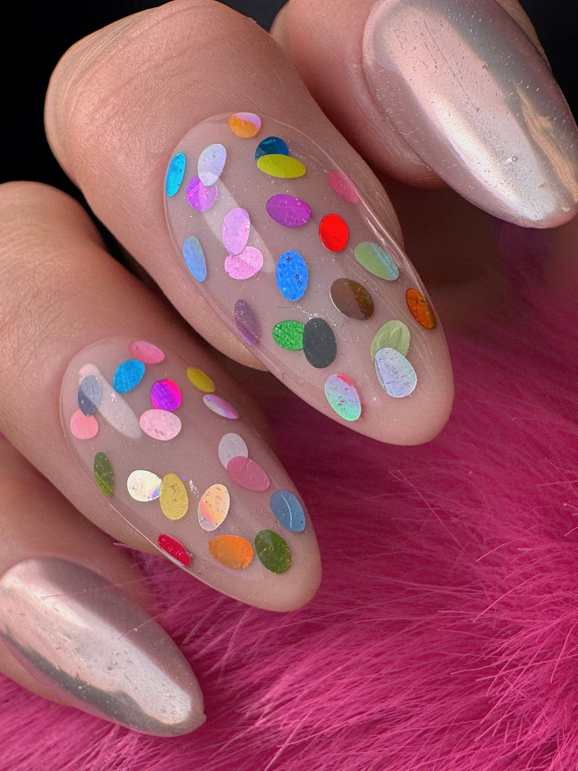 Nails with colorful oval glitter design on a pink fur background