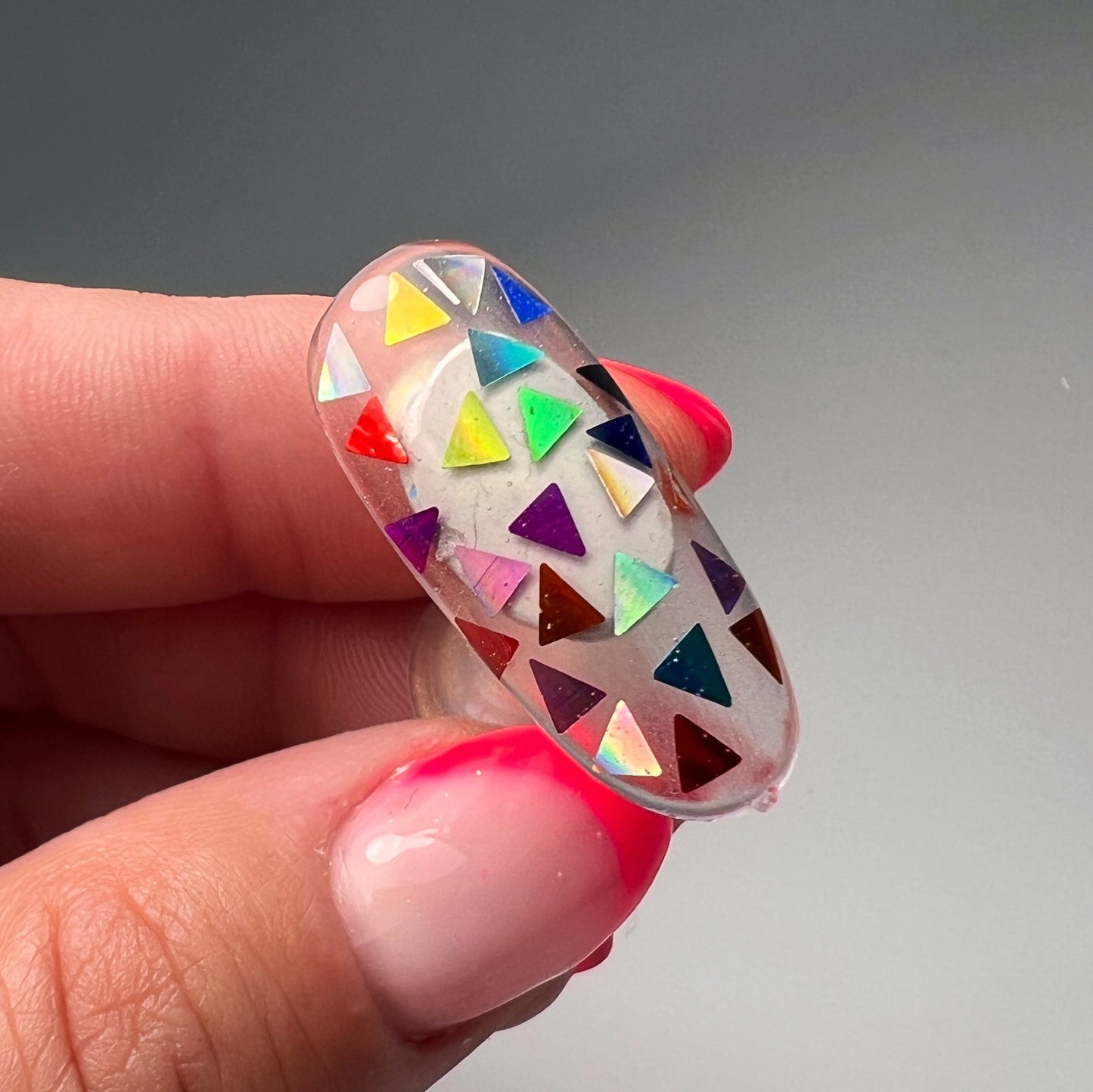 Hand holding decorated nail tip. 