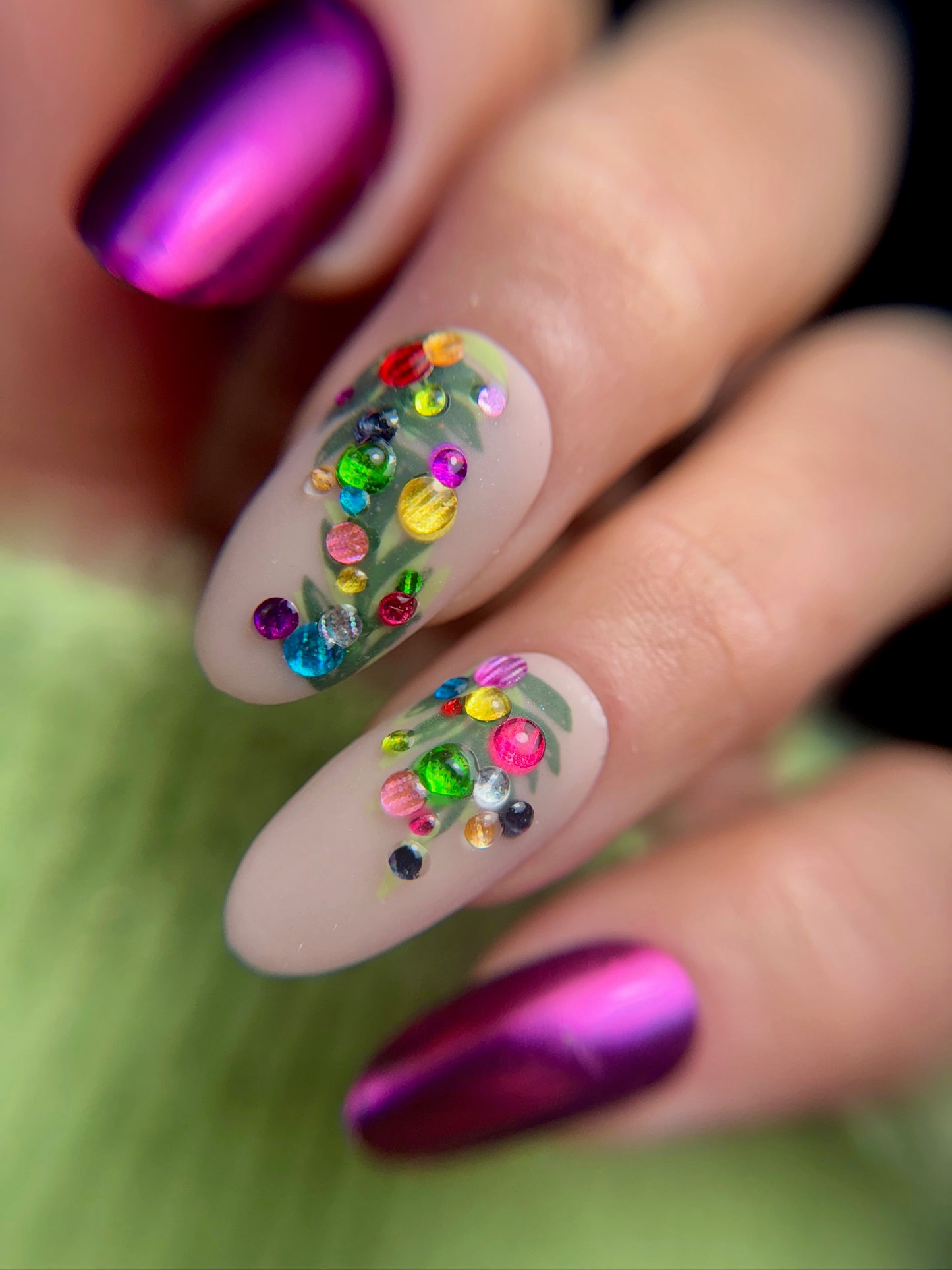 Nail art with colorful 3D bauble design  on a blurred green background