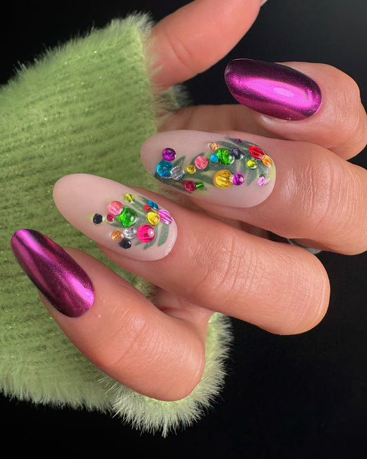 Close-up of a hand with colorful nail art on a green textured background