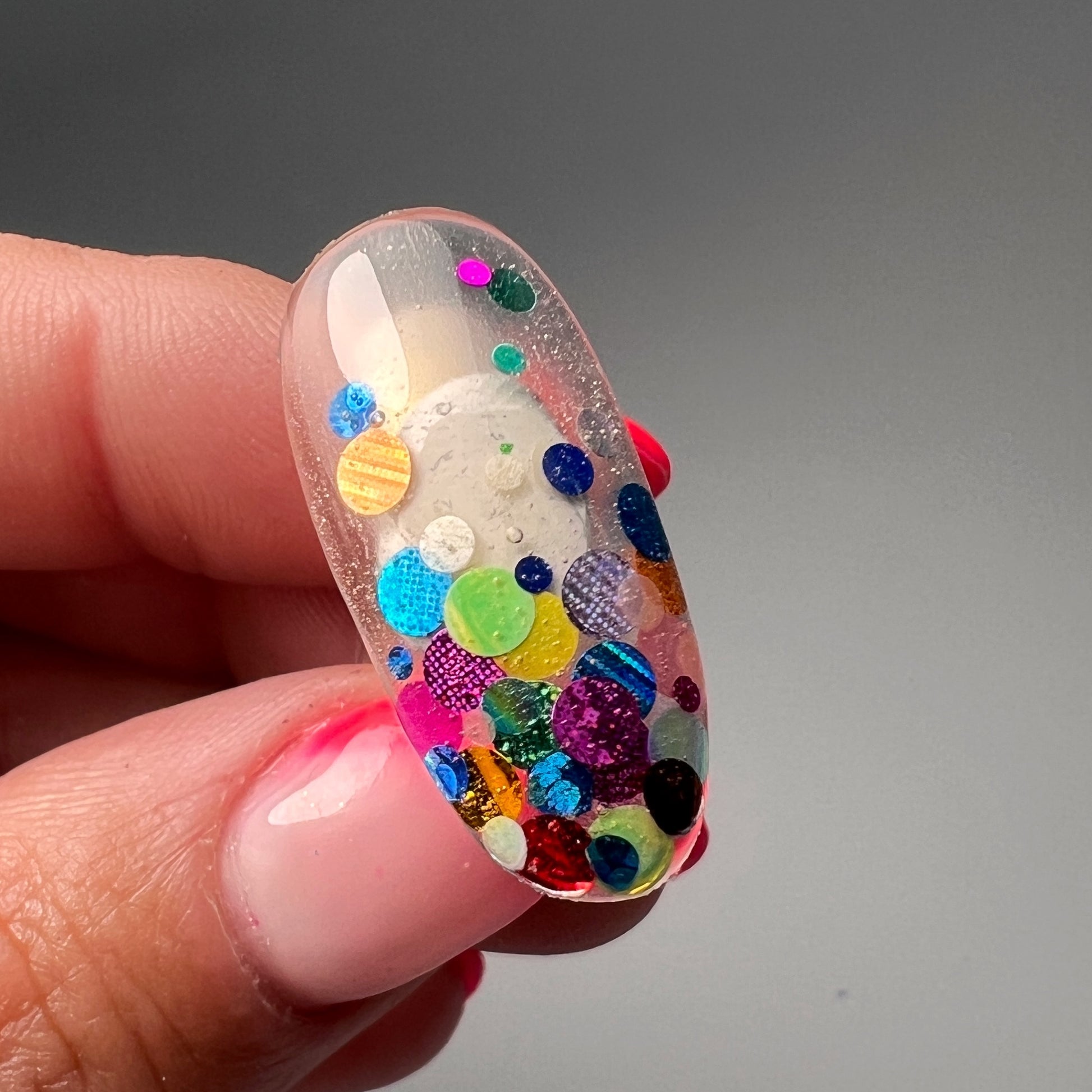 Hand holding decorated nail tip. 