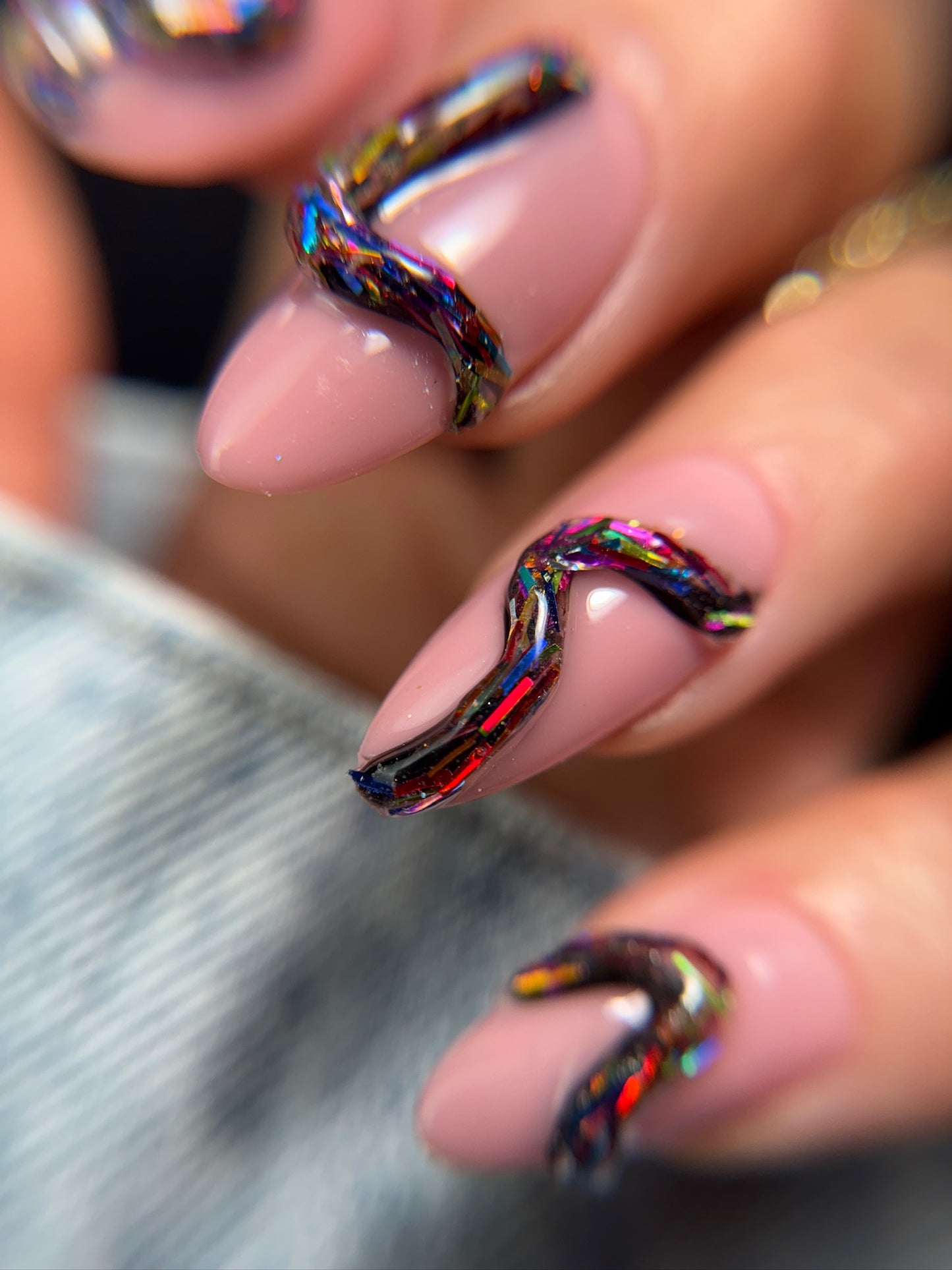 Close-up of a hand with 3D multicolor nail art on a blurred background