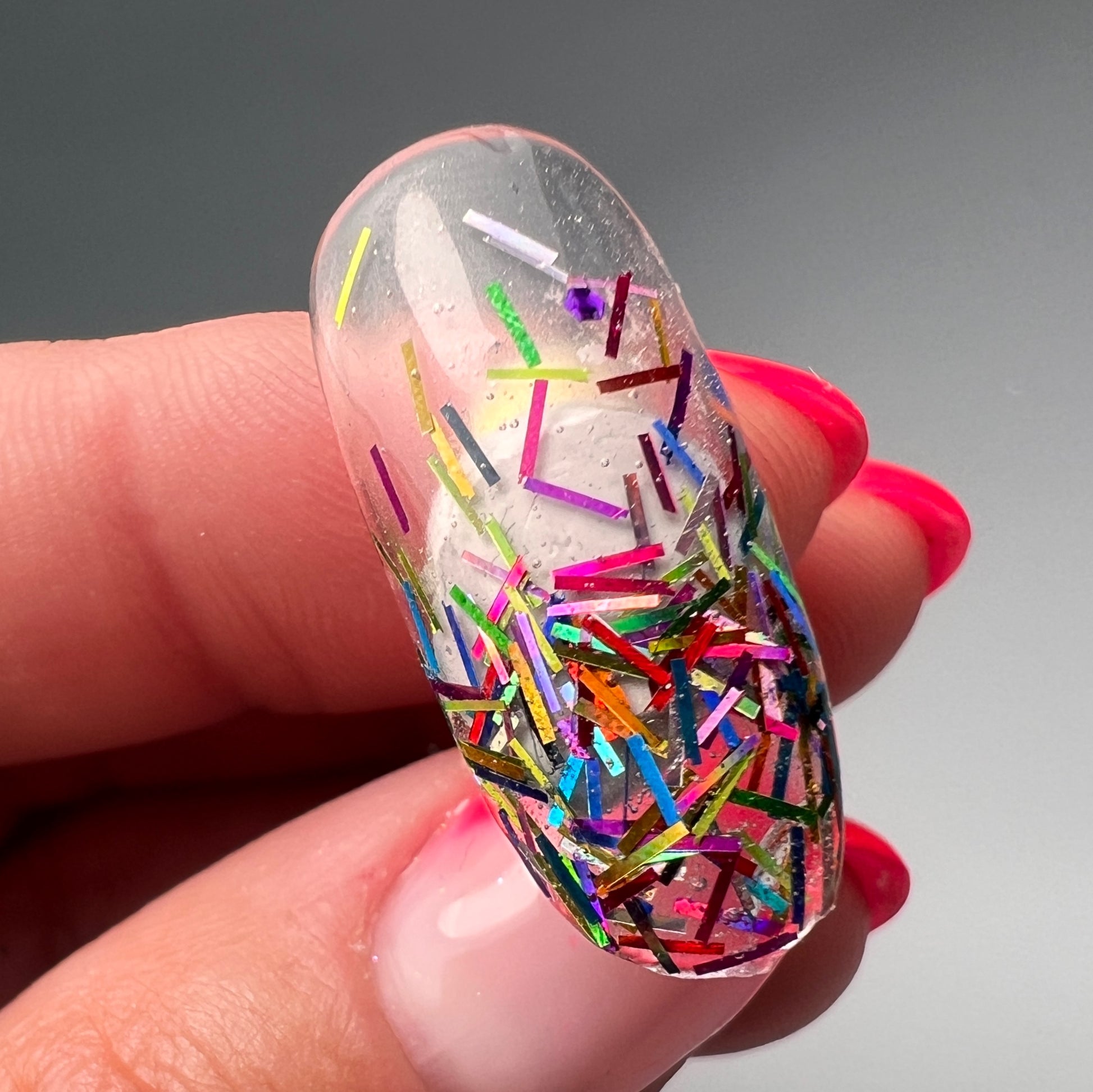Hand holding decorated nail tip. 
