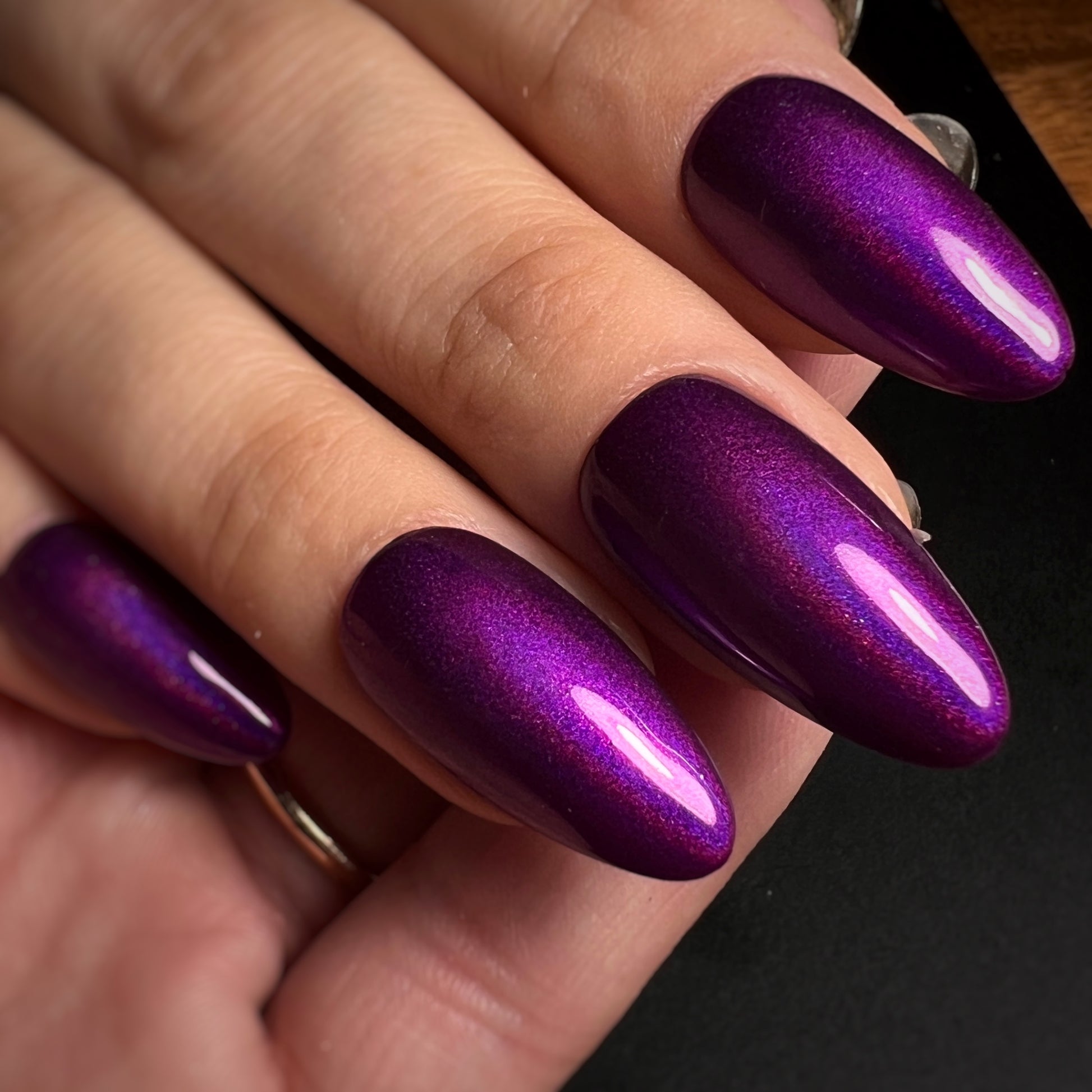 Close-up of a hand with purple glittery nails on a dark background