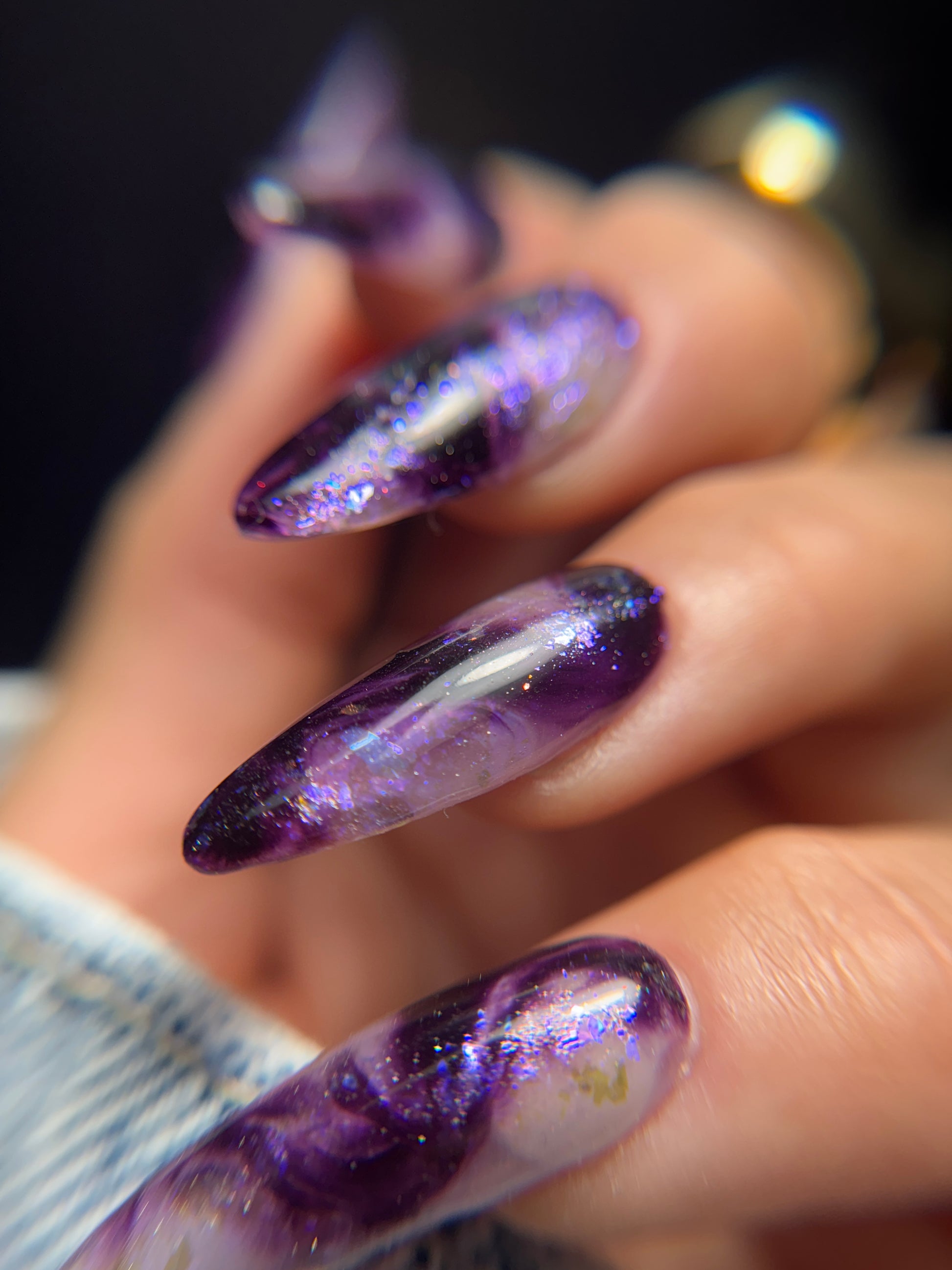 Close-up of a hand with purple marble nail art.