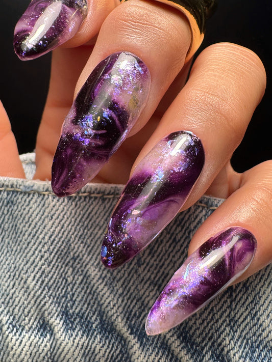Nails with purple and white marble design on a denim background