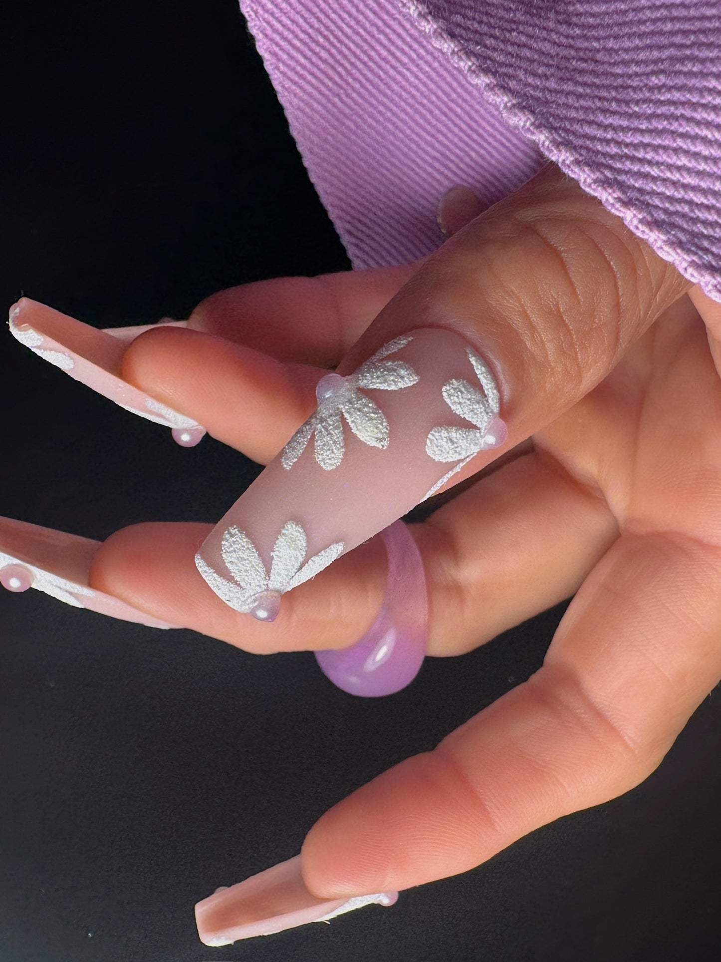 Close-up of a hand with decorative nail art on a black background